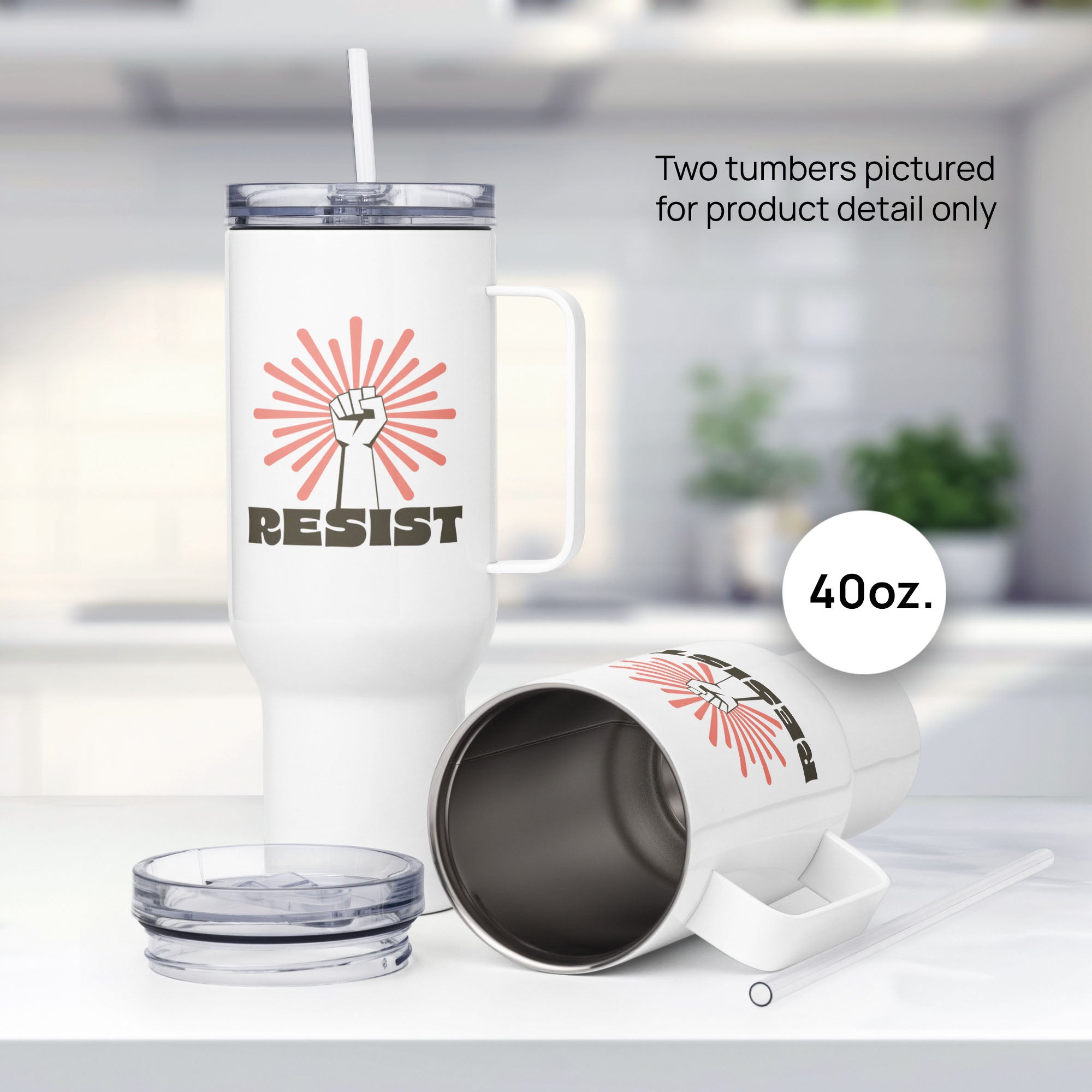Pair of 40 ounce white stainless steel tumblers with handles, with graphic text "resist" below a raised fist and coral color burst, showing product detail.