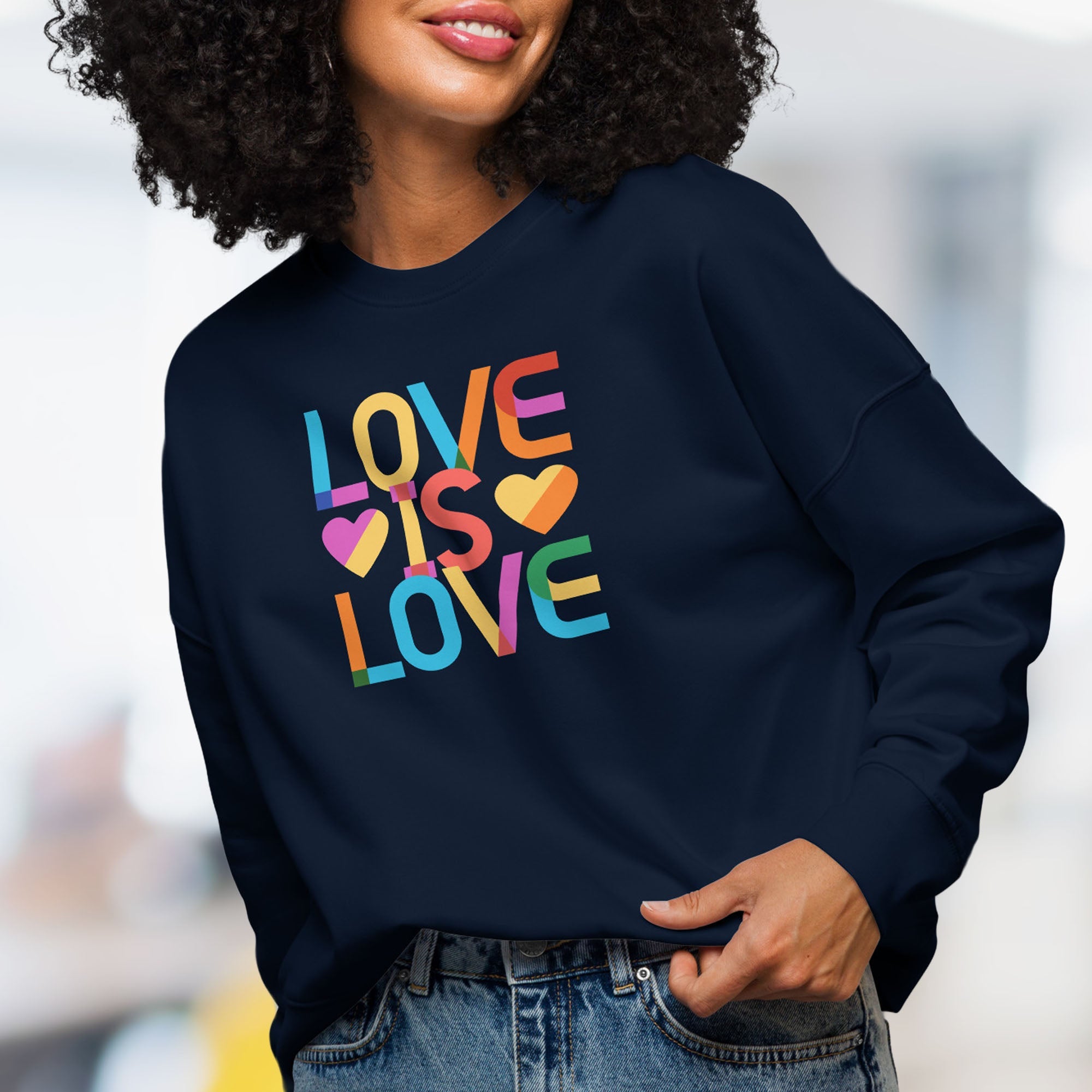 Female model wearing navy sweatshirt with rainbow text that reads "love is love."