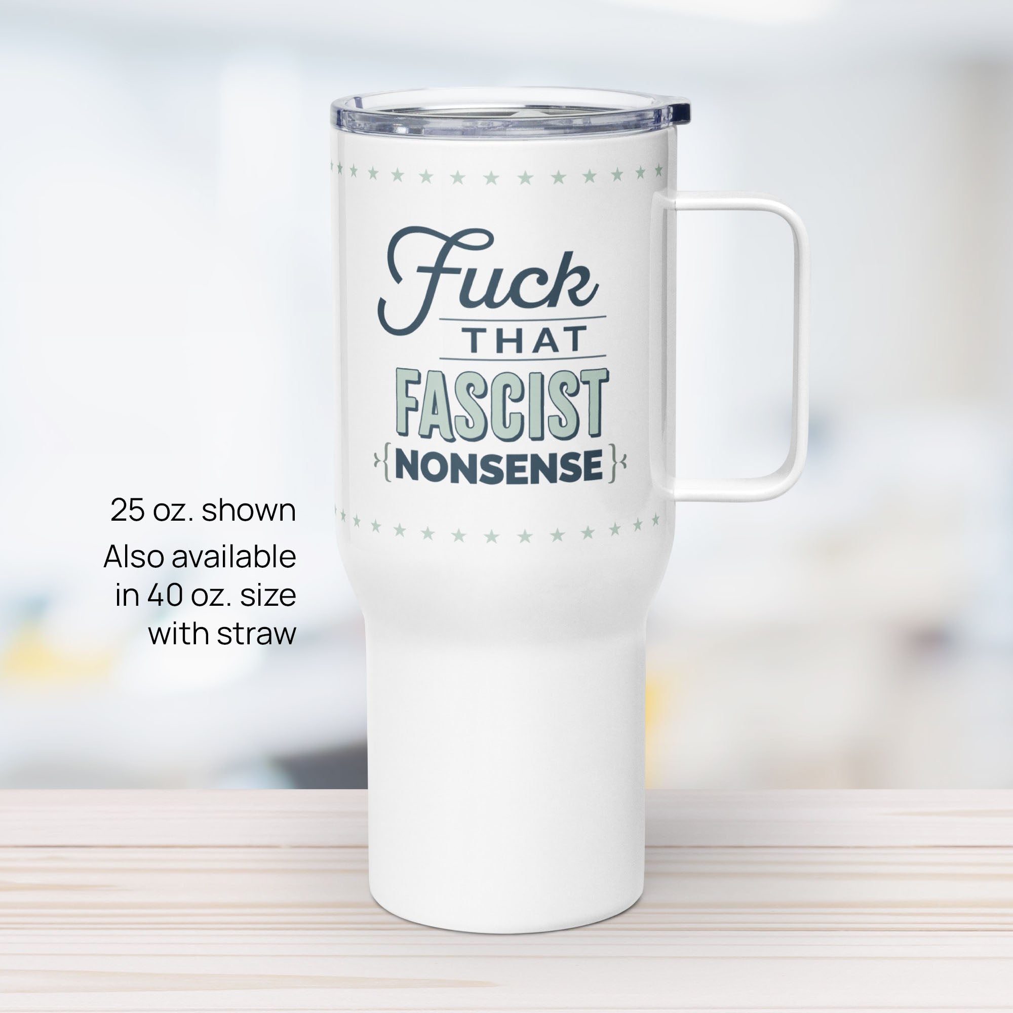 25 ounce white insulated travel tumbler with handle featuring the bold quote “Fuck That Fascist Nonsense” in blue and mint green text, on a counter in an office.