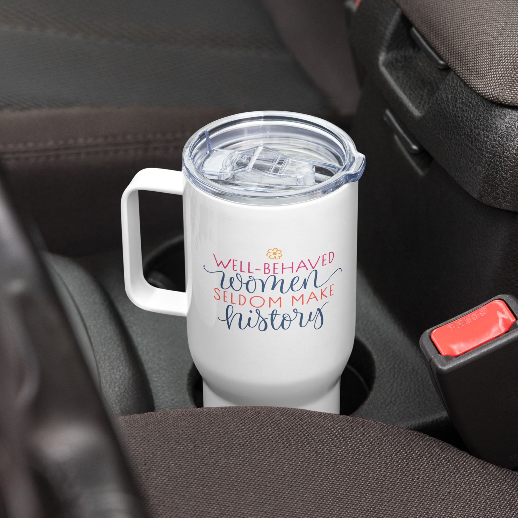 25 ounce white insulated travel tumbler with handle featuring the quote “Well-Behaved Women Seldom Make History” in colorful stylized text block, in a car cup holder.