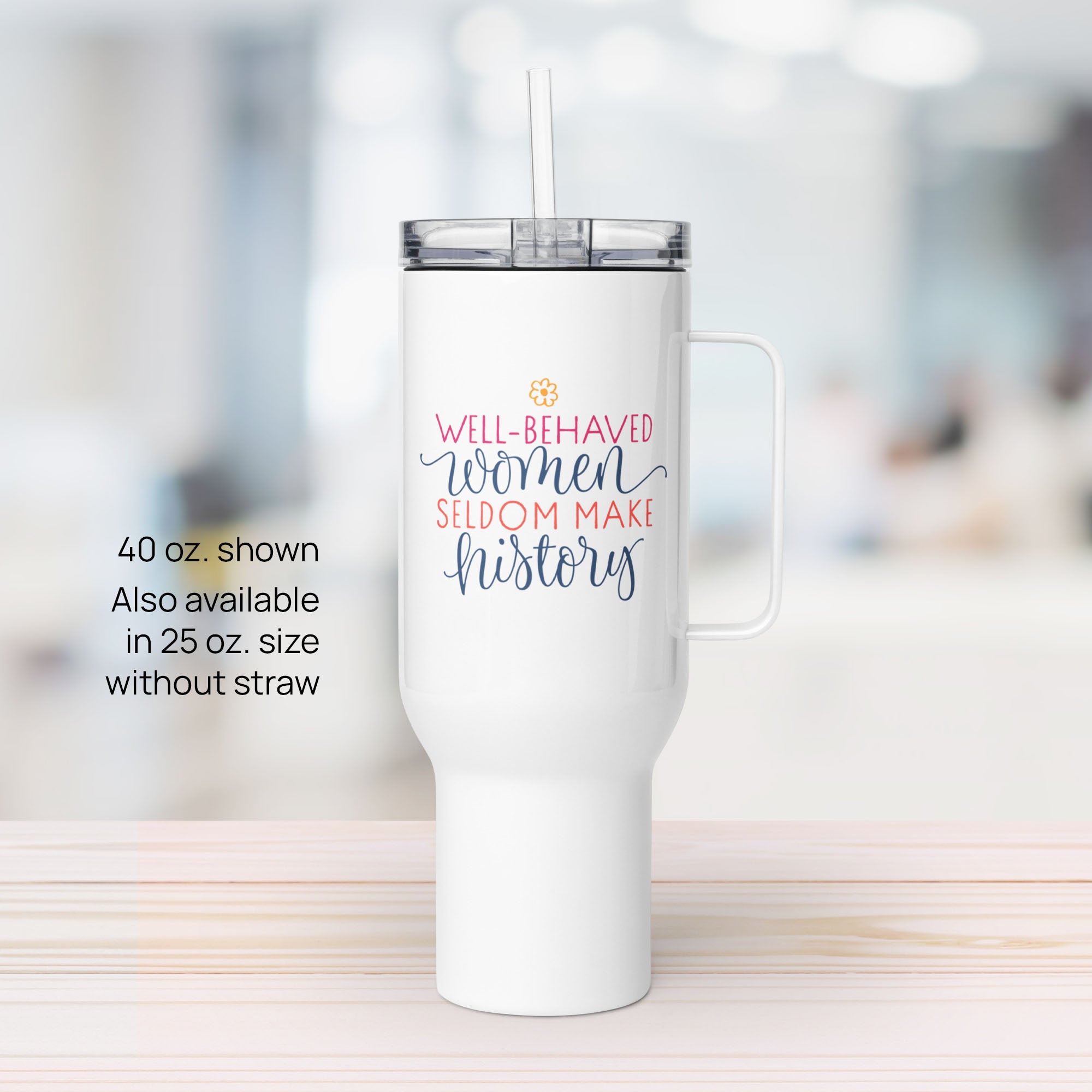 40 ounce white insulated travel tumbler with handle featuring the quote “Well-Behaved Women Seldom Make History” in colorful stylized text block, on a counter in an office.