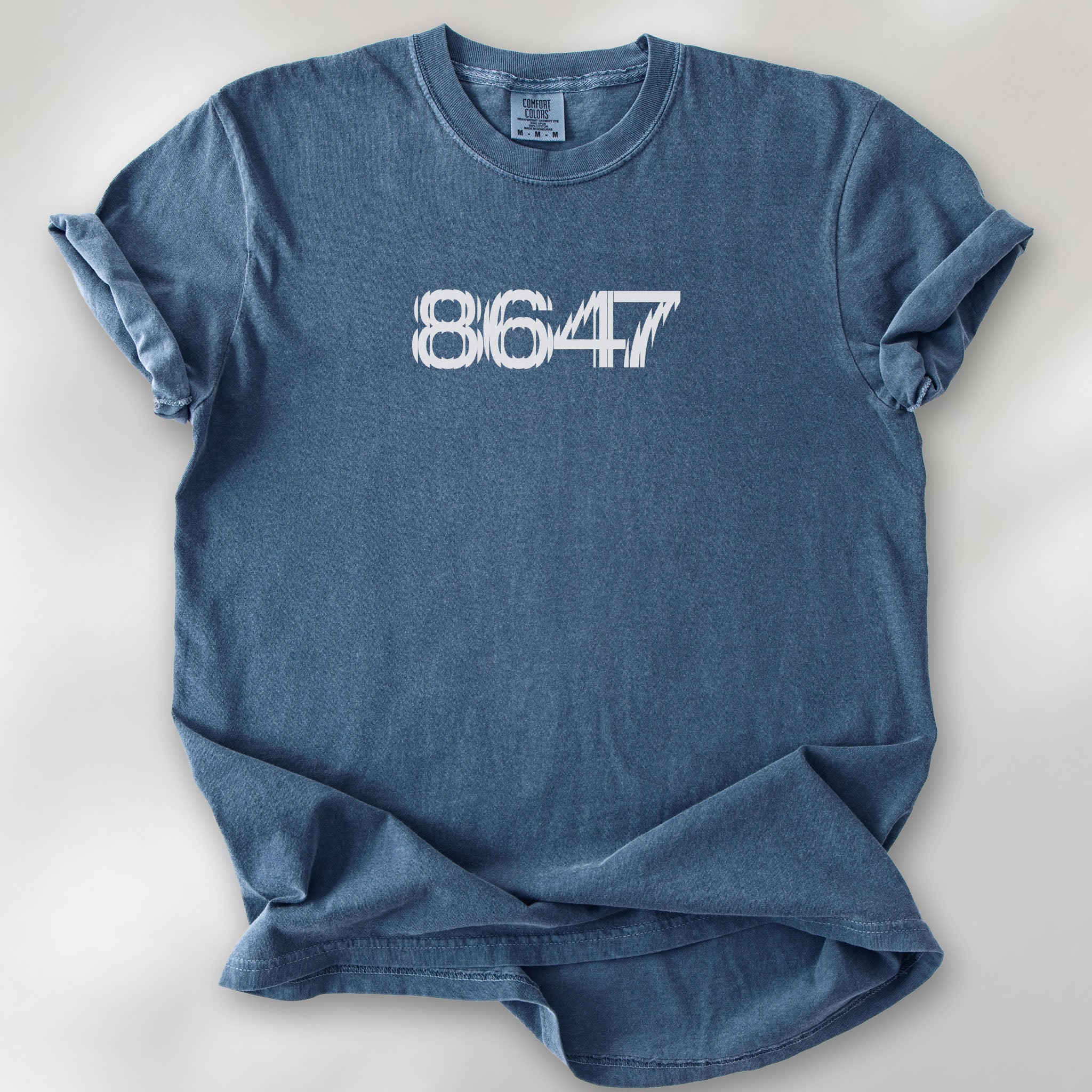 Denim unisex t-shirt featuring the number “8647” in bold, clean typography with glass block effect, referencing Trump impeachment.