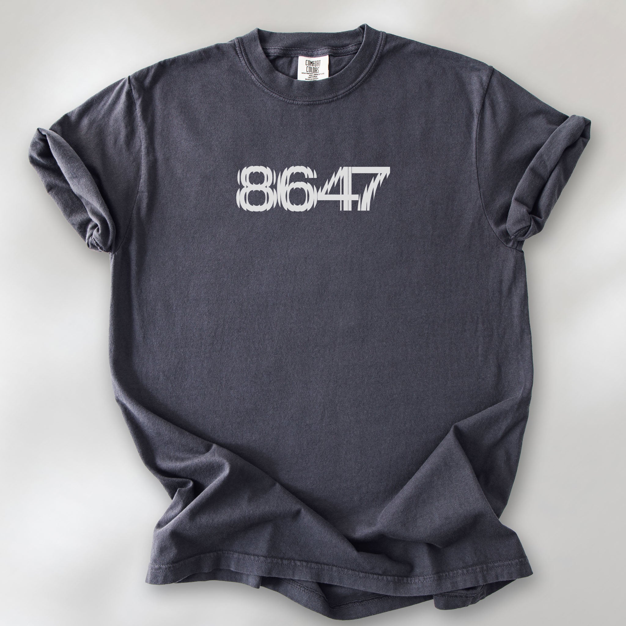 Graphite unisex t-shirt featuring the number “8647” in bold, clean typography with glass block effect, referencing Trump impeachment.
