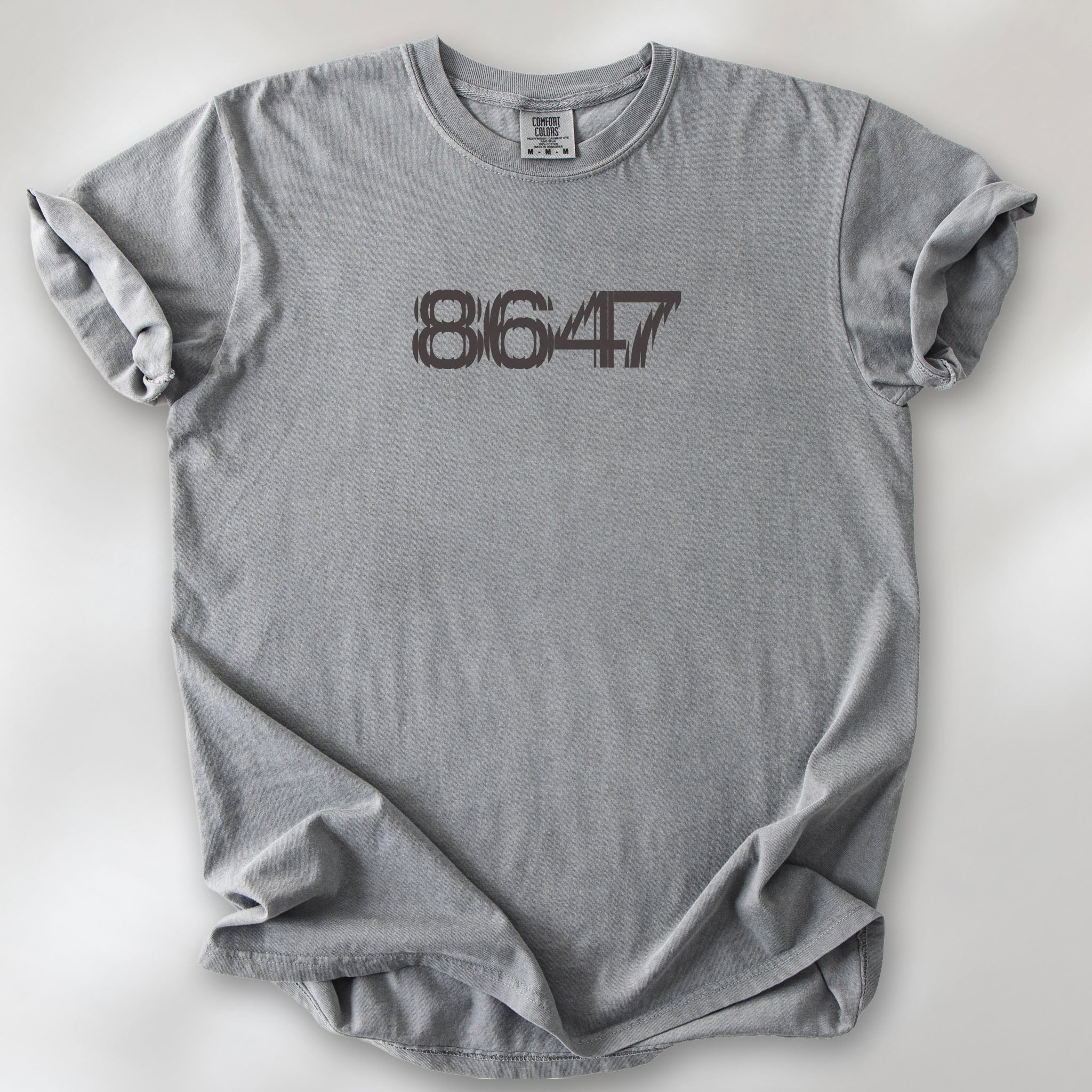 Grey unisex t-shirt featuring the number “8647” in bold, clean typography with glass block effect, referencing Trump impeachment.