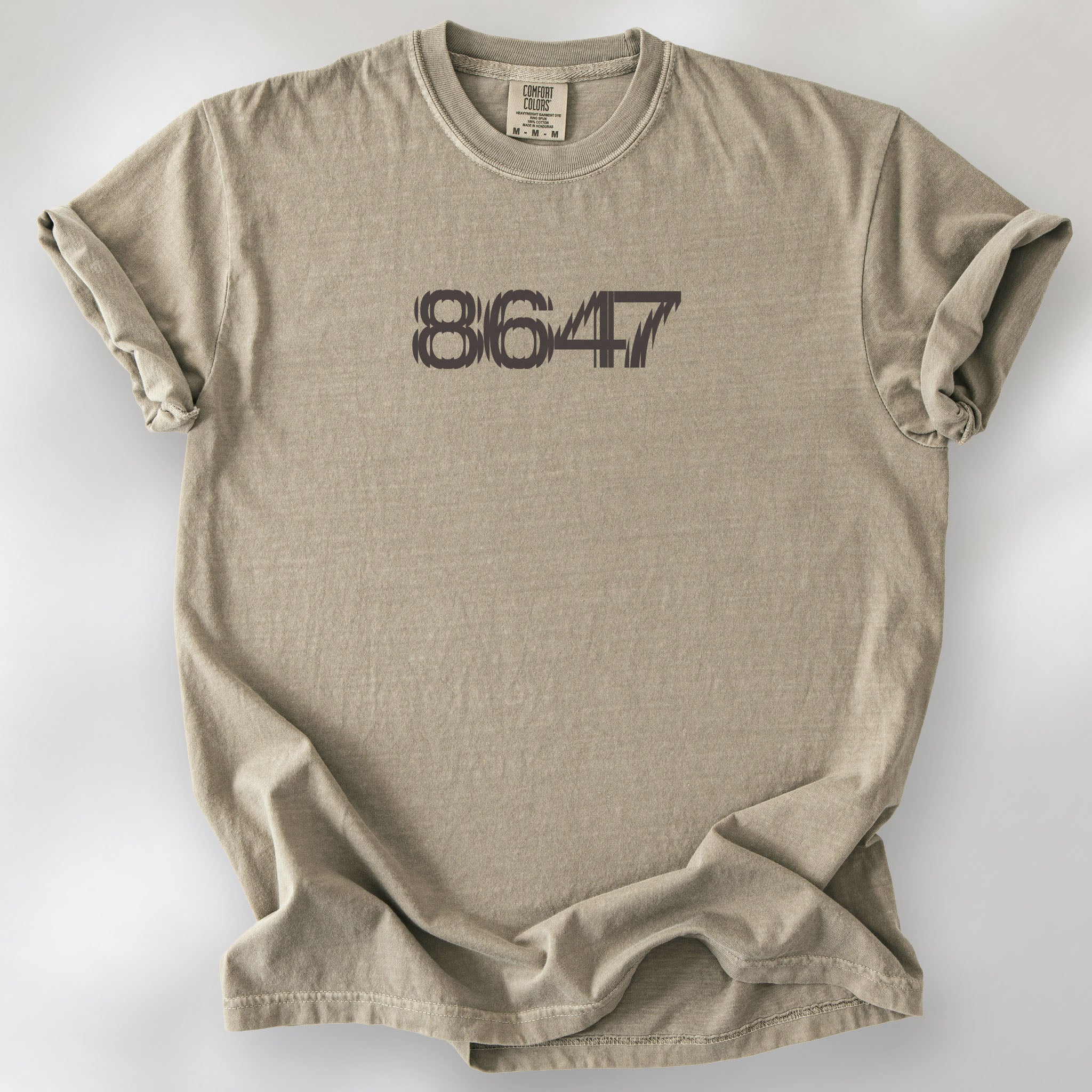 Khaki unisex t-shirt featuring the number “8647” in bold, clean typography with glass block effect, referencing Trump impeachment.