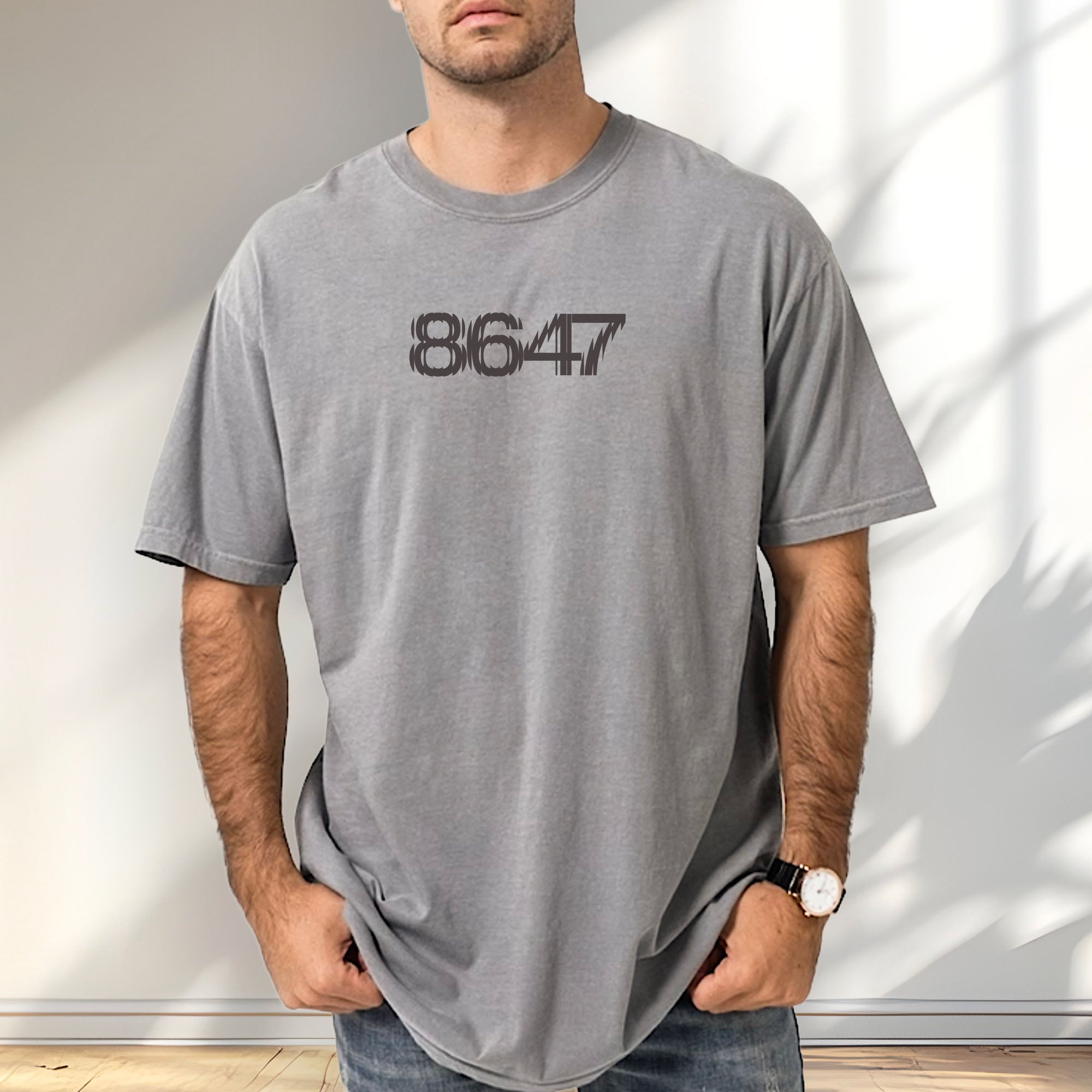 Male model wearing grey t-shirt featuring the number “8647” in bold, clean typography with glass block effect.
