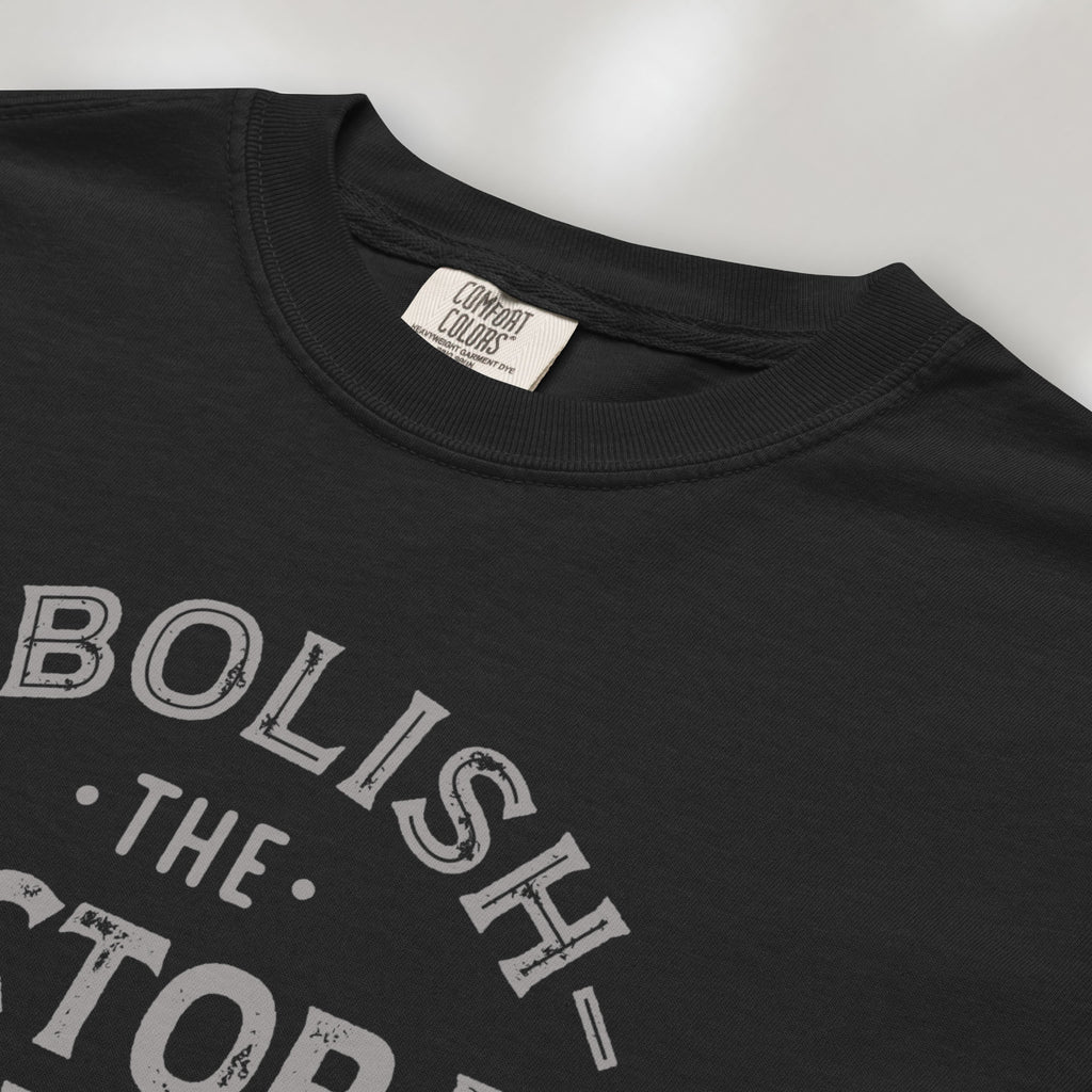 Closeup detail of black t-shirt with distressed text reading “Abolish the Electoral College One Person One Vote” in vintage style design