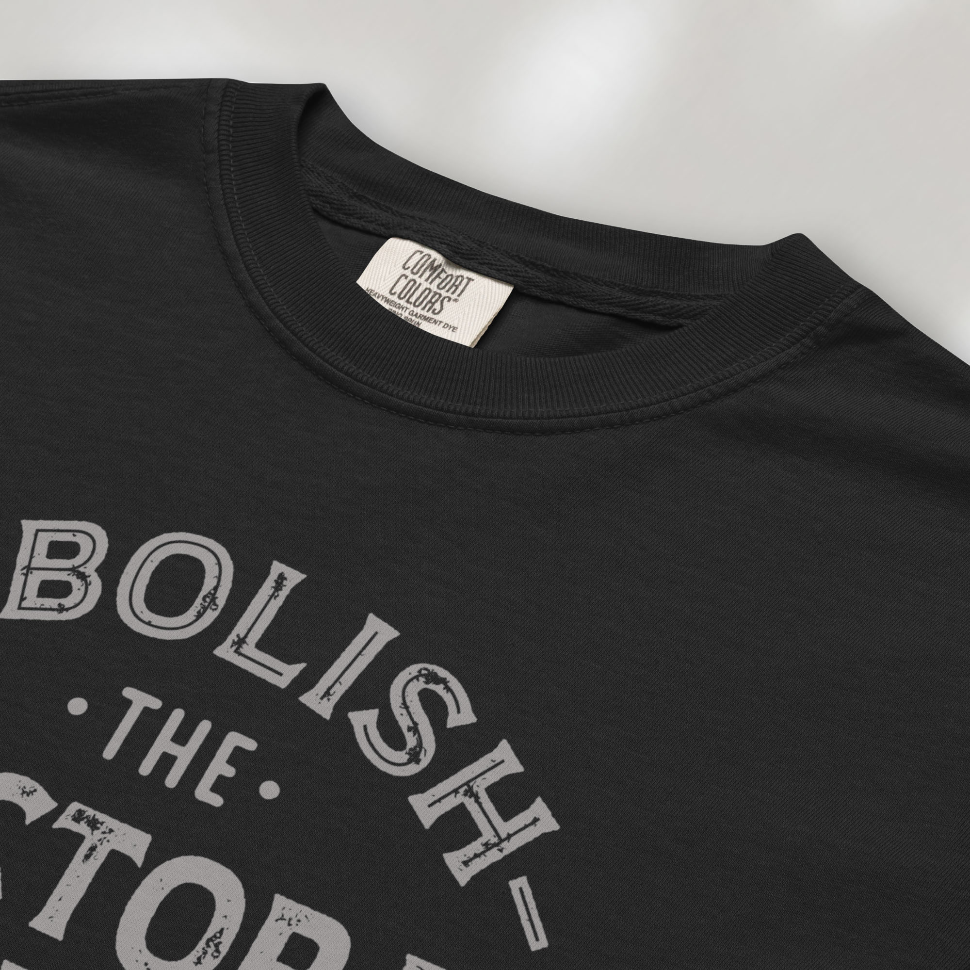 Closeup detail of black t-shirt with distressed text reading “Abolish the Electoral College One Person One Vote” in vintage style design