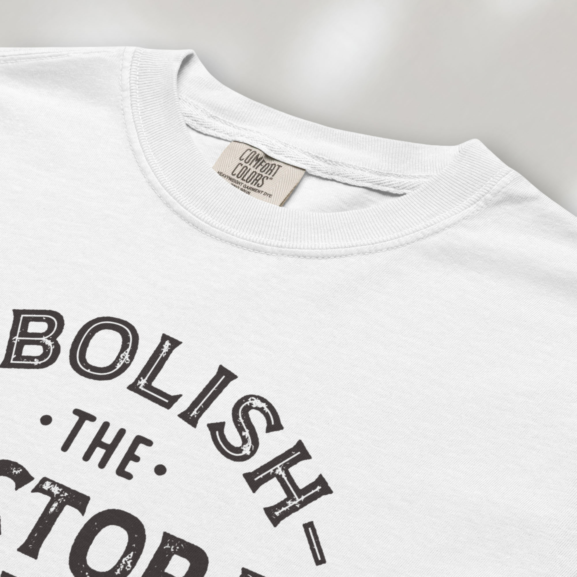 Closeup detail of white t-shirt with distressed text reading “Abolish the Electoral College One Person One Vote” in vintage style design