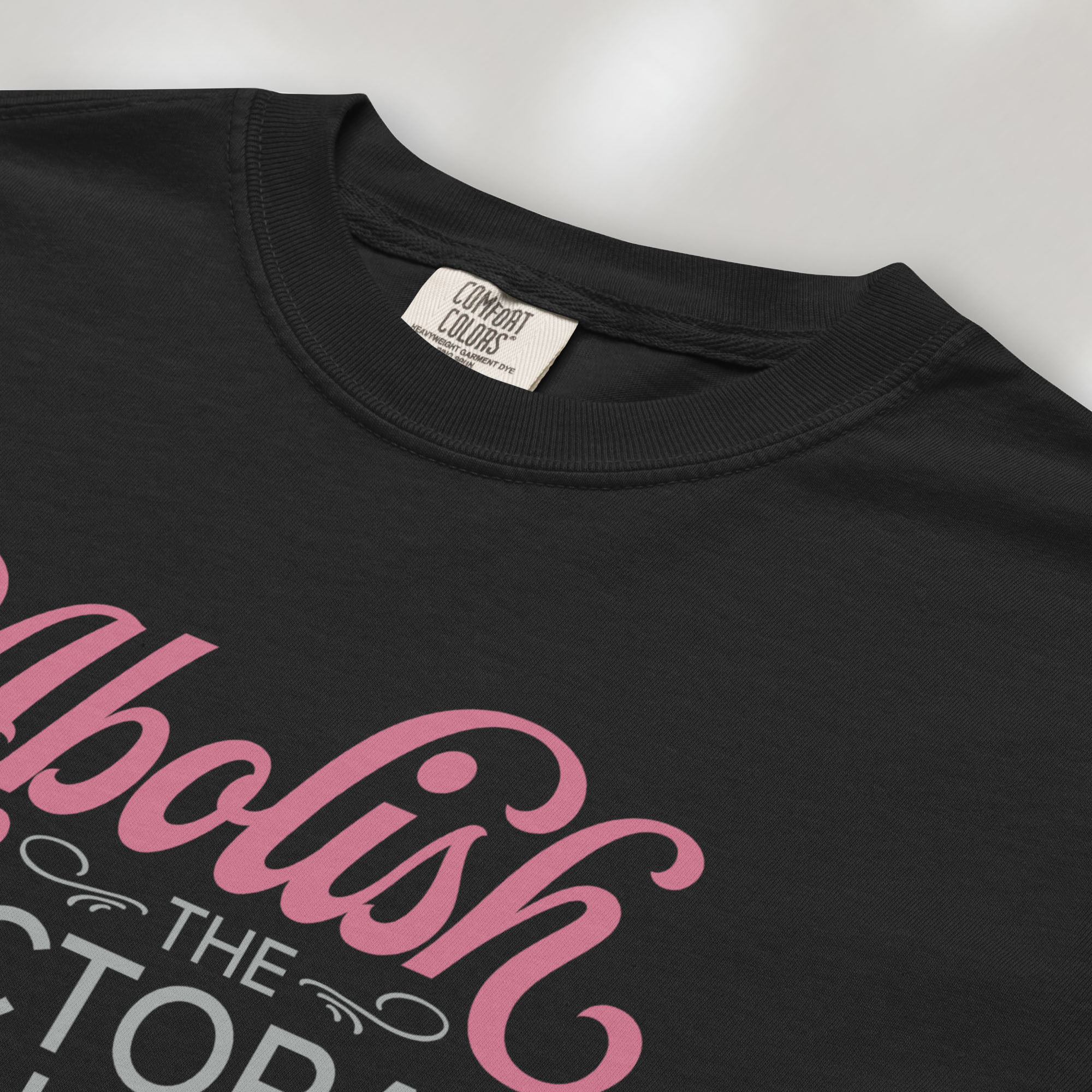 Closeup detail of black t-shirt with stylized text reading “Abolish the Electoral College” in muted red and gray.
