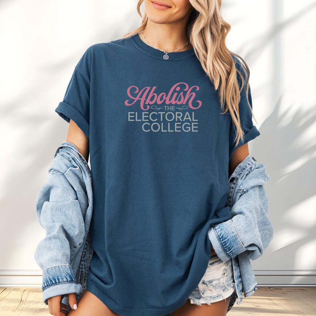 Female model wearing oversized midnight t-shirt with stylized text reading “Abolish the Electoral College” in muted red and gray.