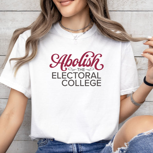 Female model wearing white t-shirt with stylized text reading “Abolish the Electoral College” in muted red and gray.