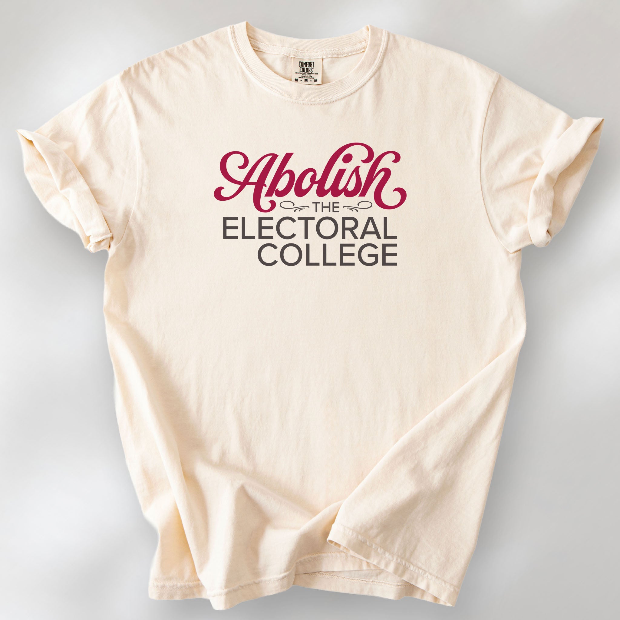 Ivory t-shirt with stylized text reading “Abolish the Electoral College” in muted red and gray.