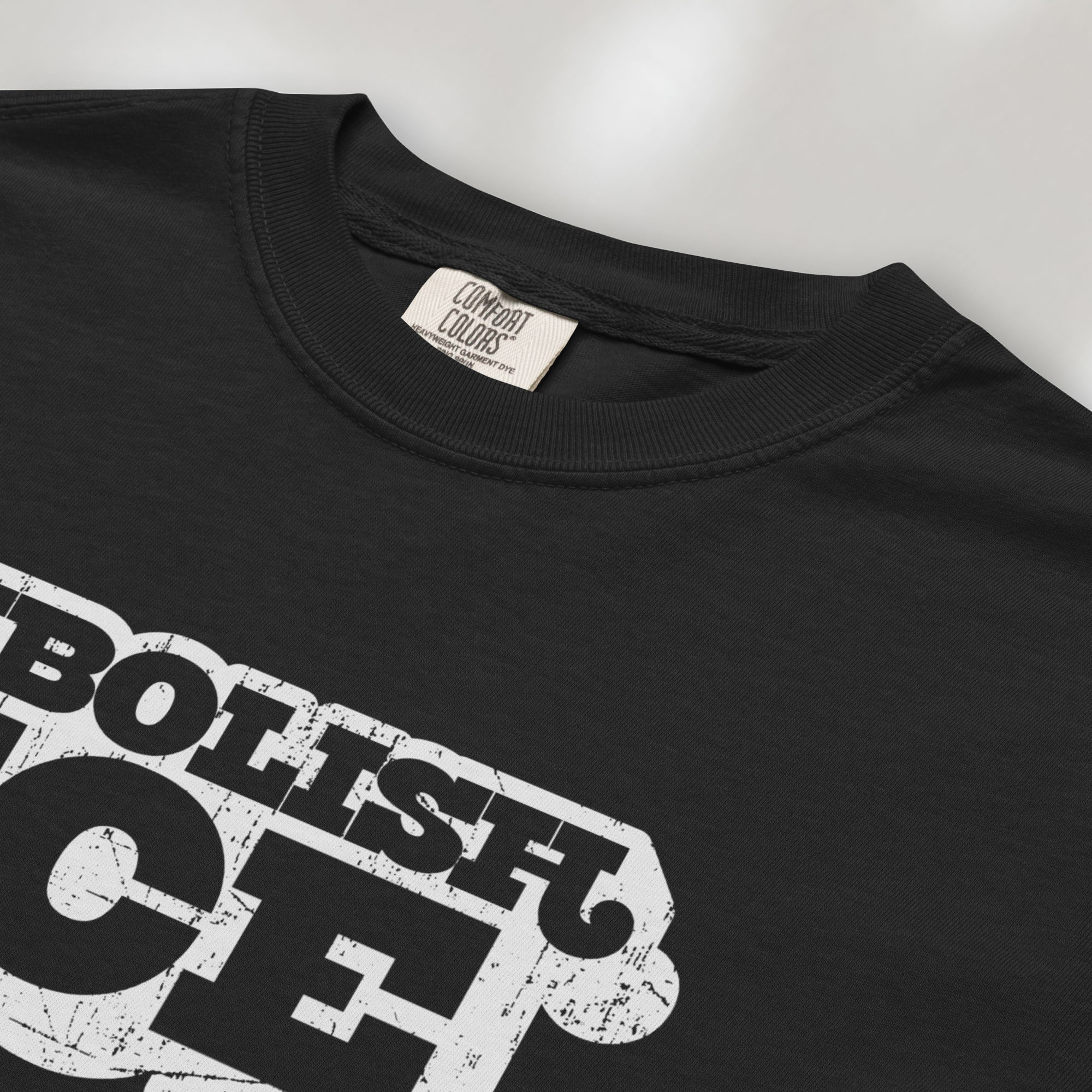 Closeup detail of black t-shirt with retro distressed text reading “Abolish ICE” for immigration justice and anti-ICE activism.