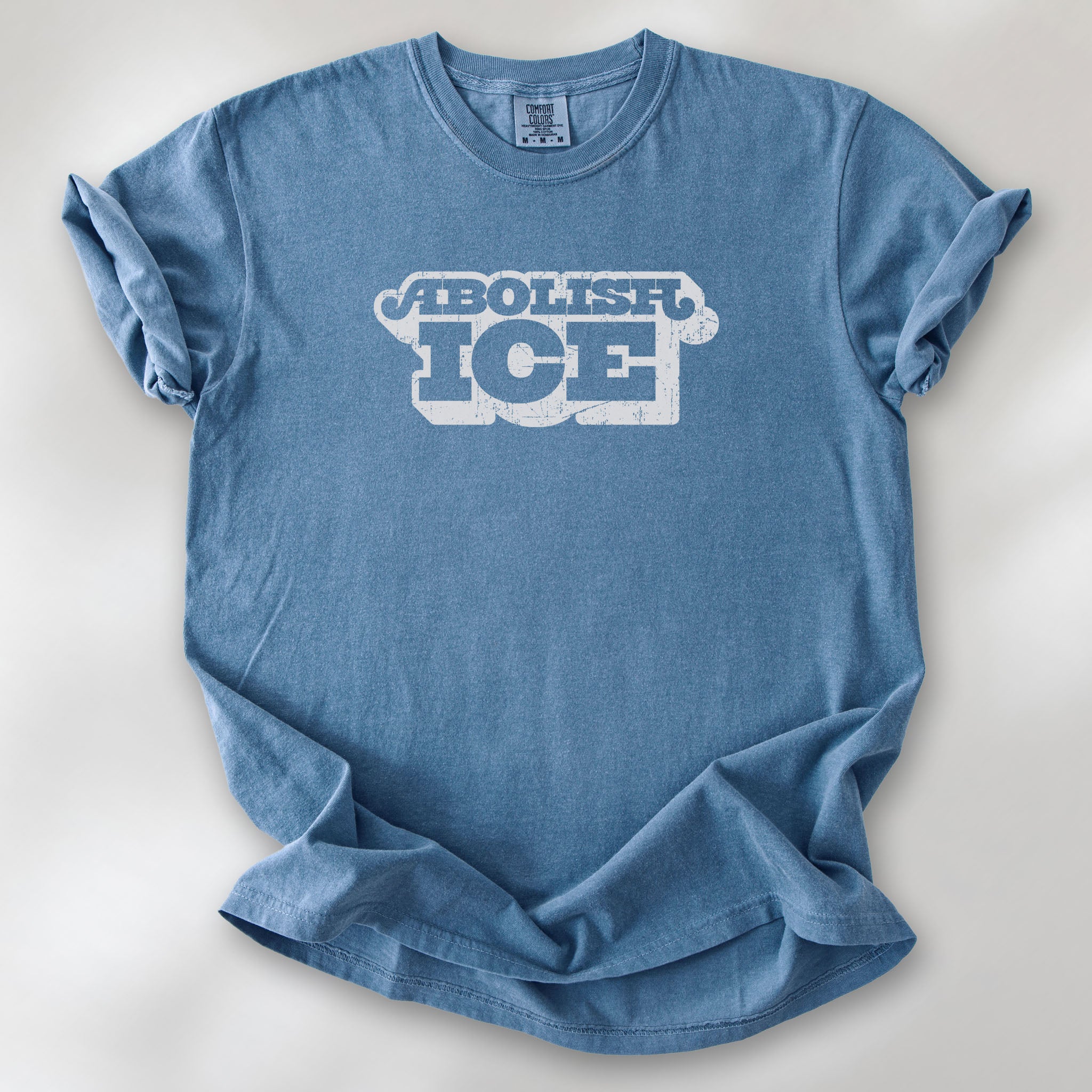 Blue jean t-shirt with retro distressed text reading “Abolish ICE” for immigration justice and anti-ICE activism.