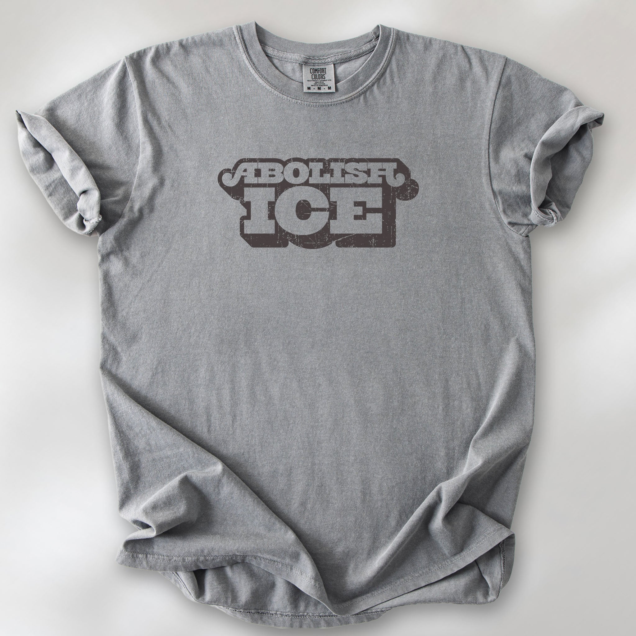 Grey t-shirt with retro distressed text reading “Abolish ICE” for immigration justice and anti-ICE activism.