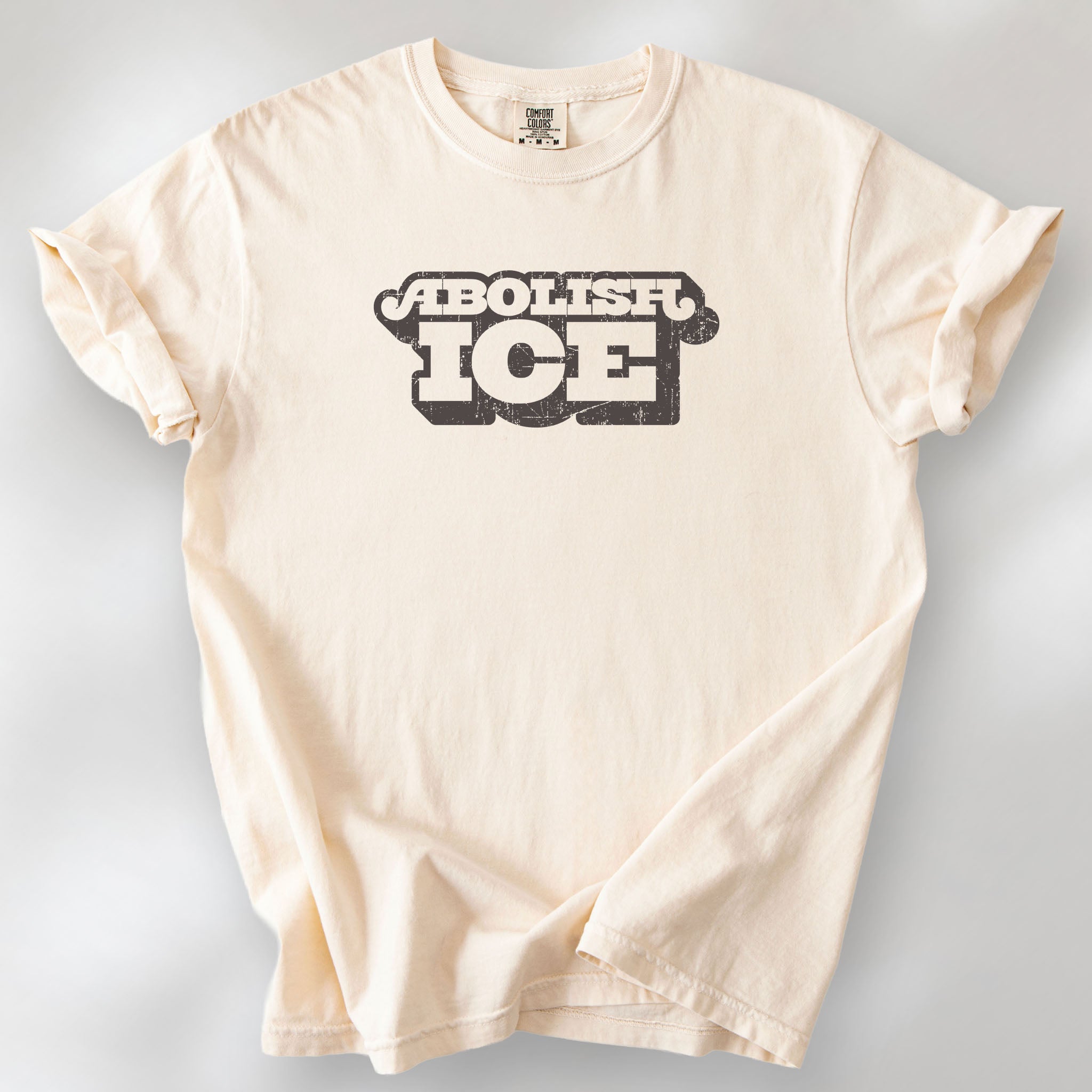 Ivory t-shirt with retro distressed text reading “Abolish ICE” for immigration justice and anti-ICE activism.