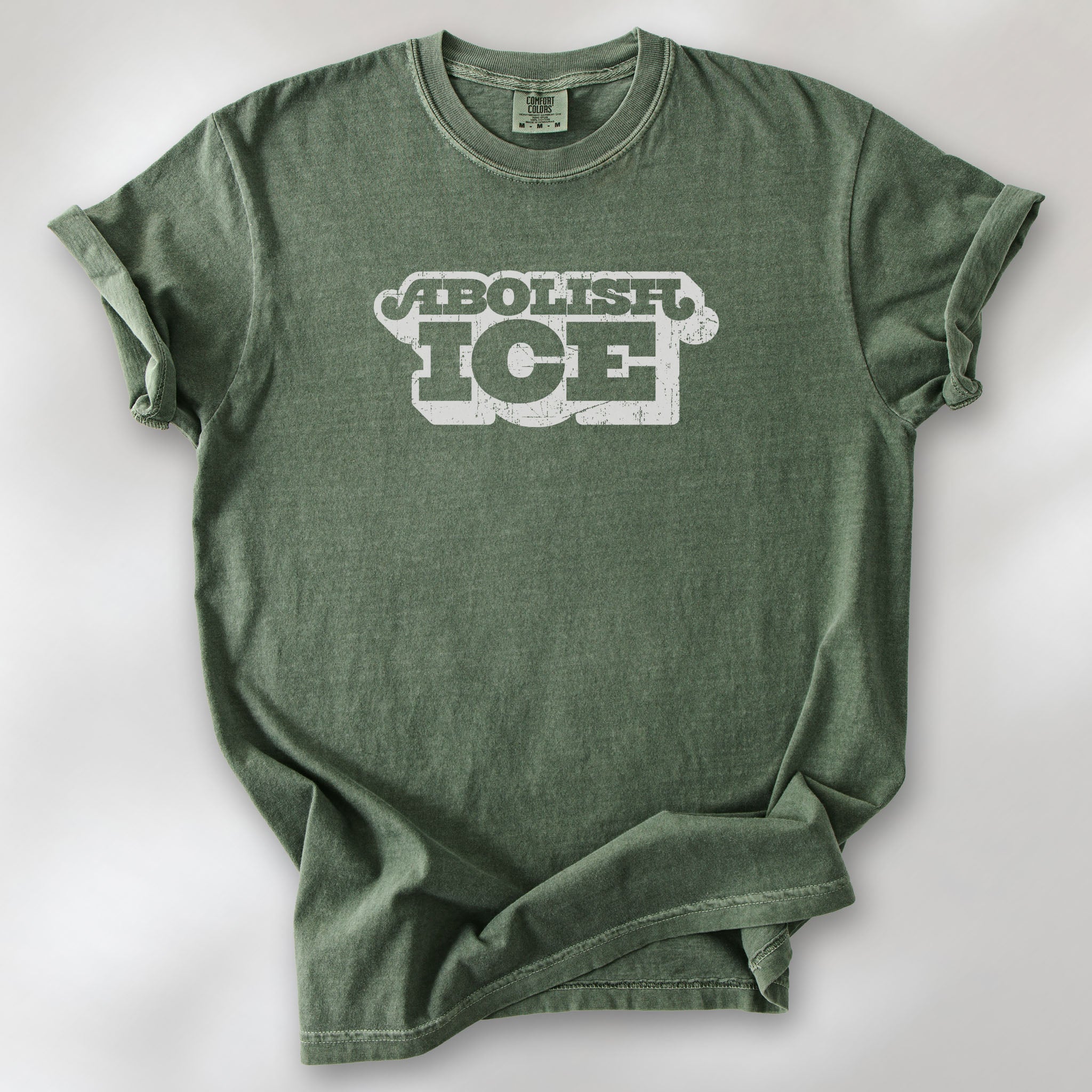 Moss t-shirt with retro distressed text reading “Abolish ICE” for immigration justice and anti-ICE activism.