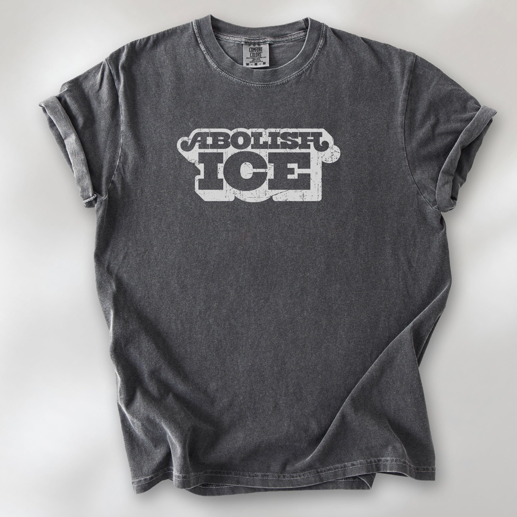 Pepper t-shirt with retro distressed text reading “Abolish ICE” for immigration justice and anti-ICE activism.