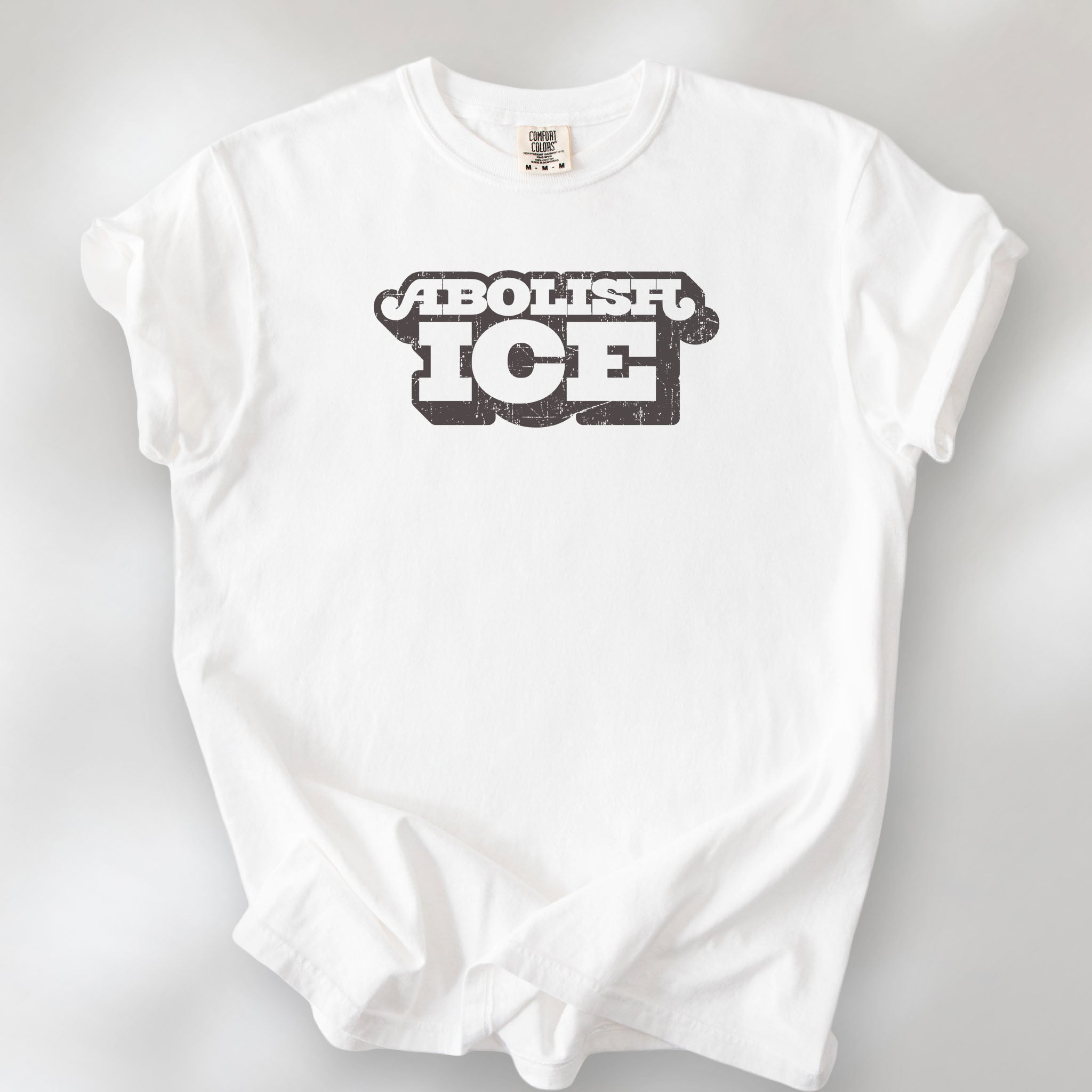 White t-shirt with retro distressed text reading “Abolish ICE” for immigration justice and anti-ICE activism.