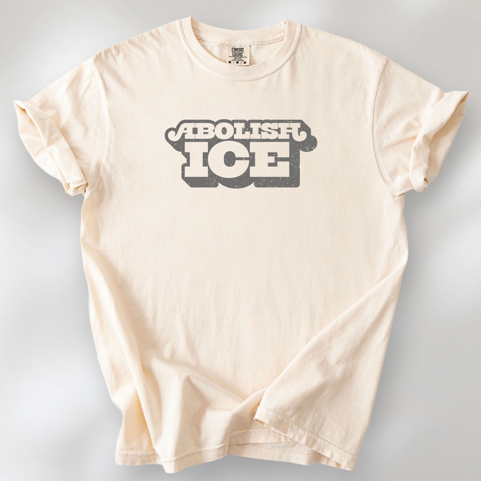 Ivory t-shirt with retro text reading “Abolish ICE” for immigration justice and anti-ICE activism.