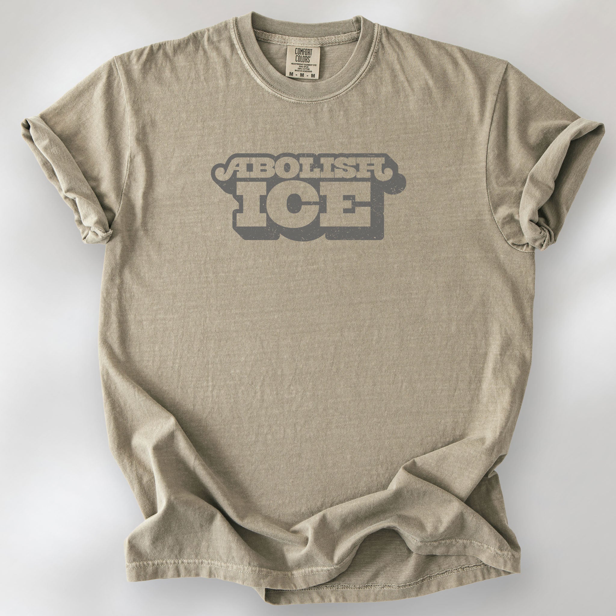 Khaki t-shirt with retro text reading “Abolish ICE” for immigration justice and anti-ICE activism.