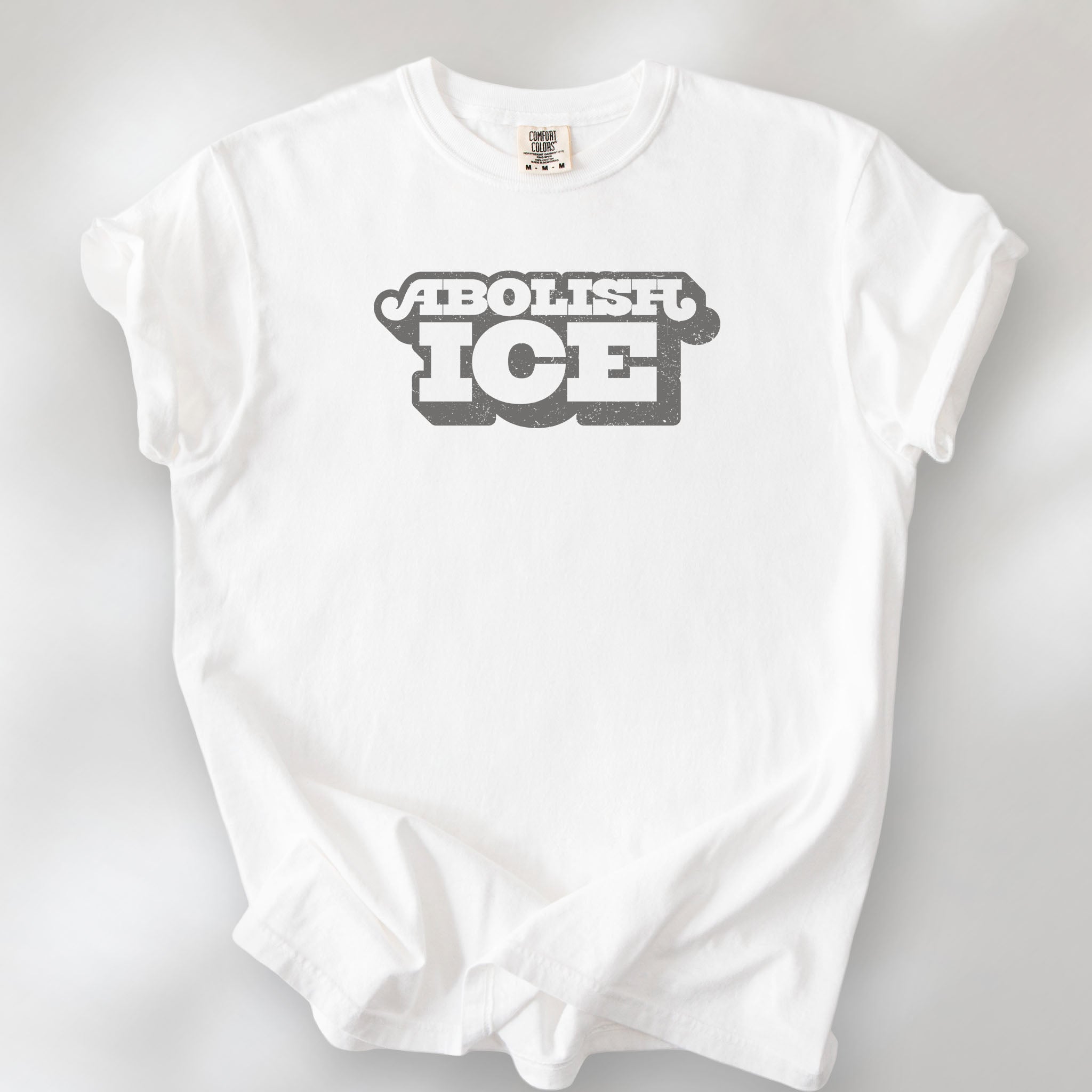 White t-shirt with retro text reading “Abolish ICE” for immigration justice and anti-ICE activism.