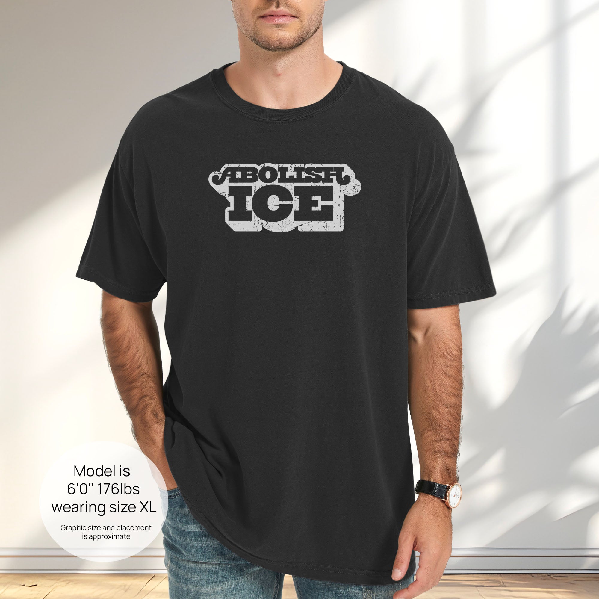 Male model wearing black t-shirt with retro distressed text reading “Abolish ICE” for immigration justice and anti-ICE activism. Includes size and fit information for the model who is 6 feet 0 inches, 176 pounds, and wearing a size XL shirt.
