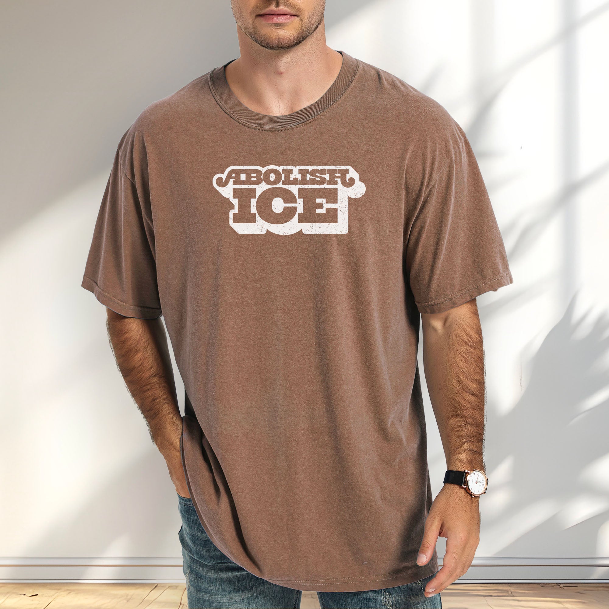 Female model wearing espresso t-shirt with retro text reading “Abolish ICE” for immigration justice and anti-ICE activism.