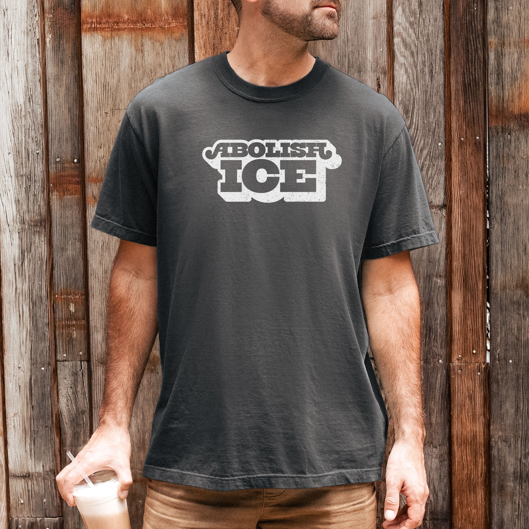 Male model wearing pepper t-shirt with retro text reading “Abolish ICE” for immigration justice and anti-ICE activism.