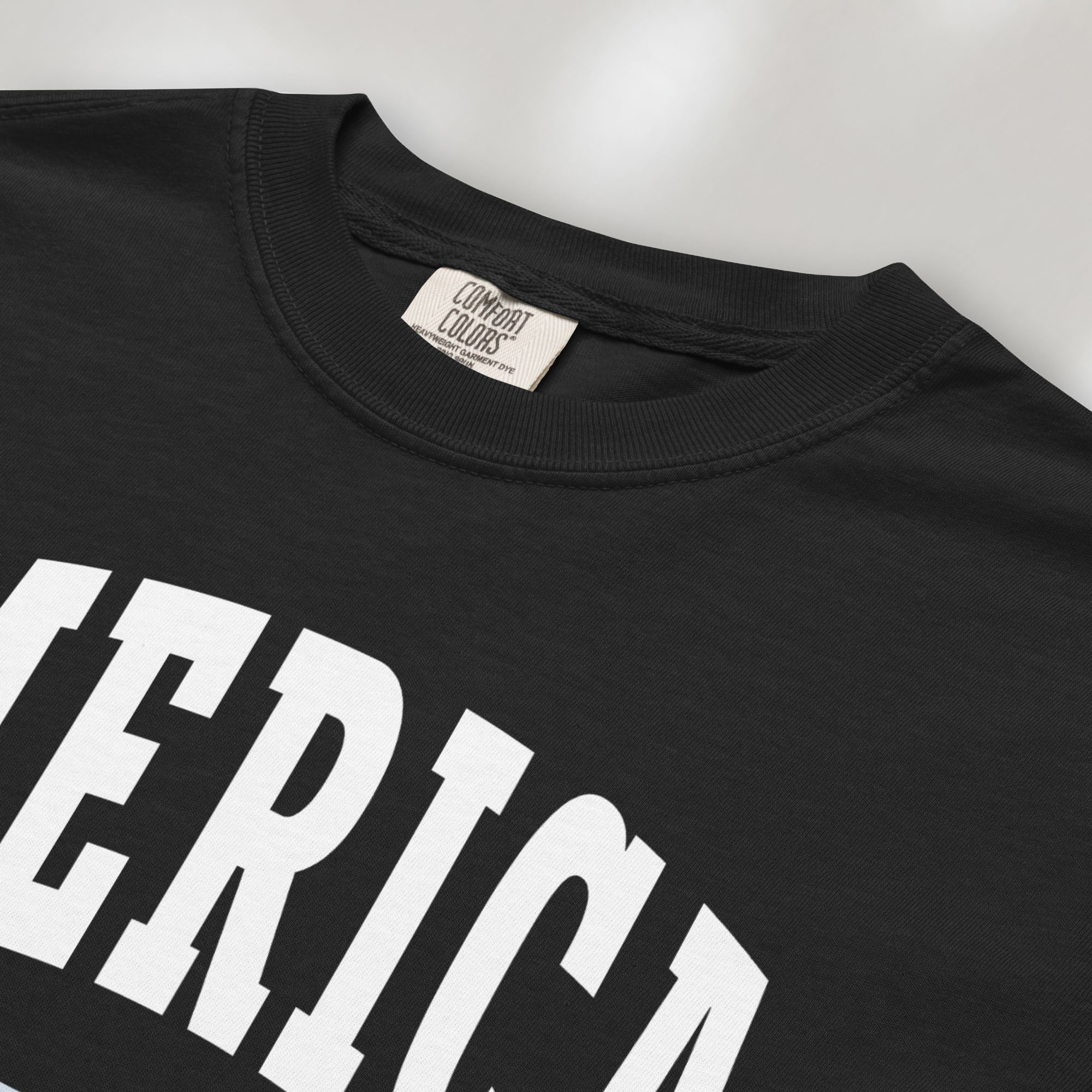 Closeup detail of black t-shirt with bold varsity text reading “America 250 — Est. 1776” in varsity style design.