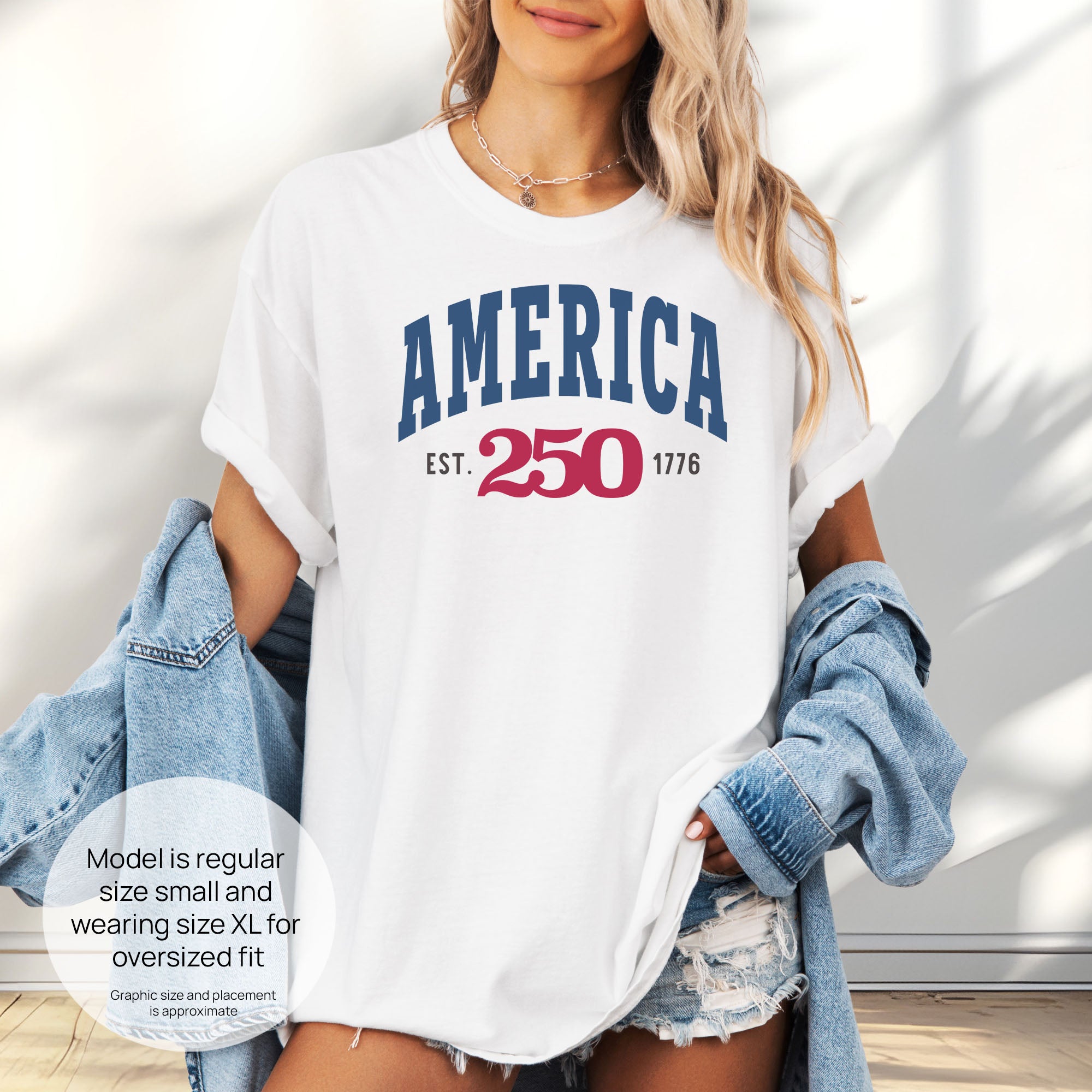 Female model wearing oversized white t-shirt with bold varsity text reading “America 250 — Est. 1776” in varsity style design. Includes size and fit information for the model who is regular size small, and wearing a size XL shirt for an oversized fit.
