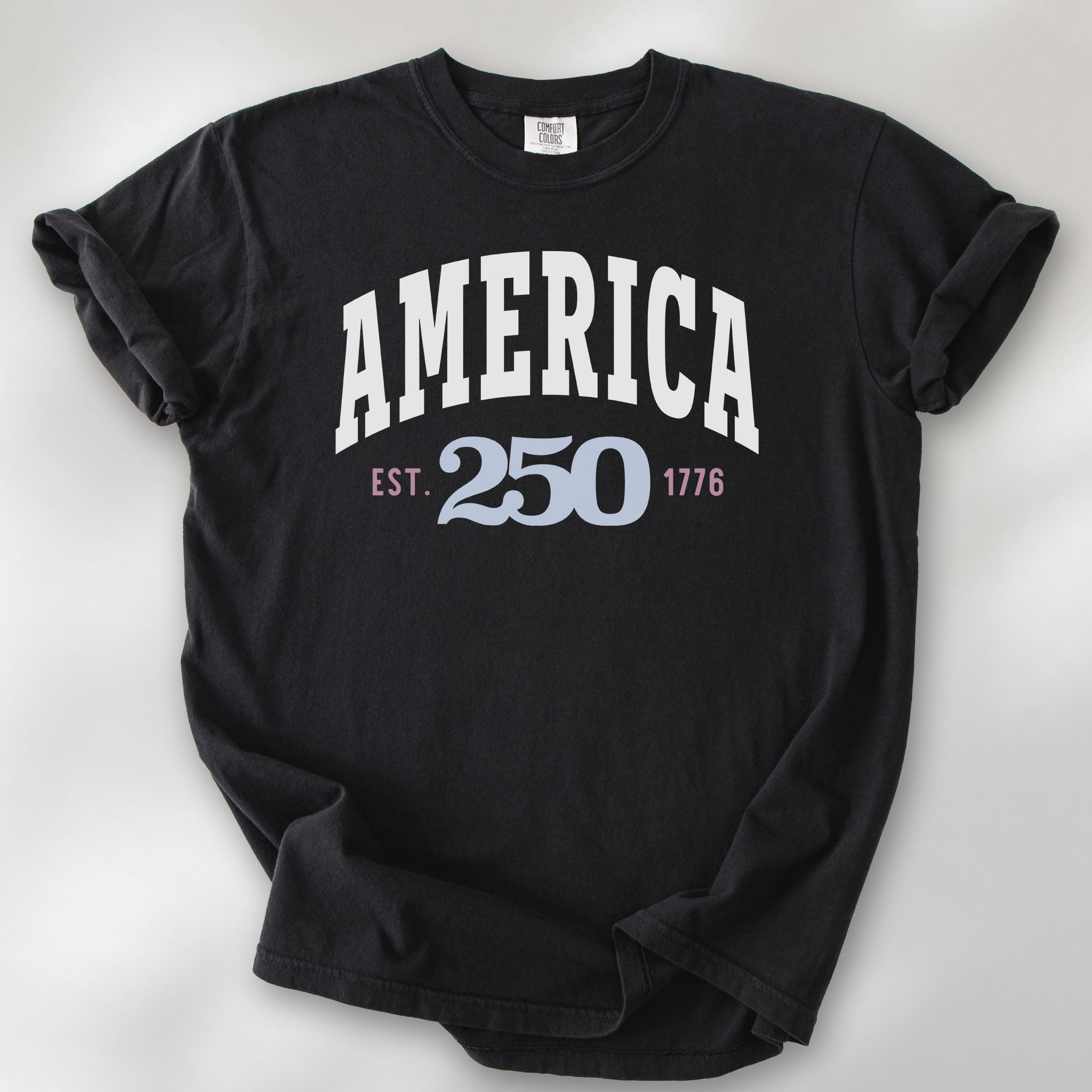 Black t-shirt with bold varsity text reading “America 250 — Est. 1776” in varsity style design. 