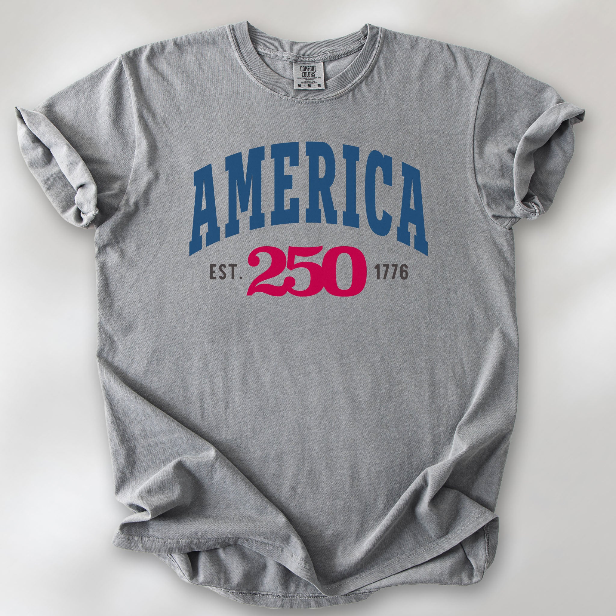 Grey t-shirt with bold varsity text reading “America 250 — Est. 1776” in varsity style design. 