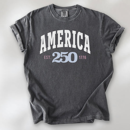 Pepper t-shirt with bold varsity text reading “America 250 — Est. 1776” in varsity style design. 