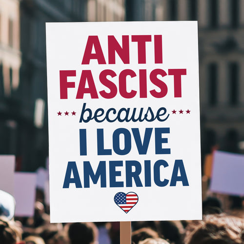Protest sign reading “Anti-Fascist Because I Love America” in red and blue lettering with patriotic heart design, anti-Trump rally poster, held high above a crowd.