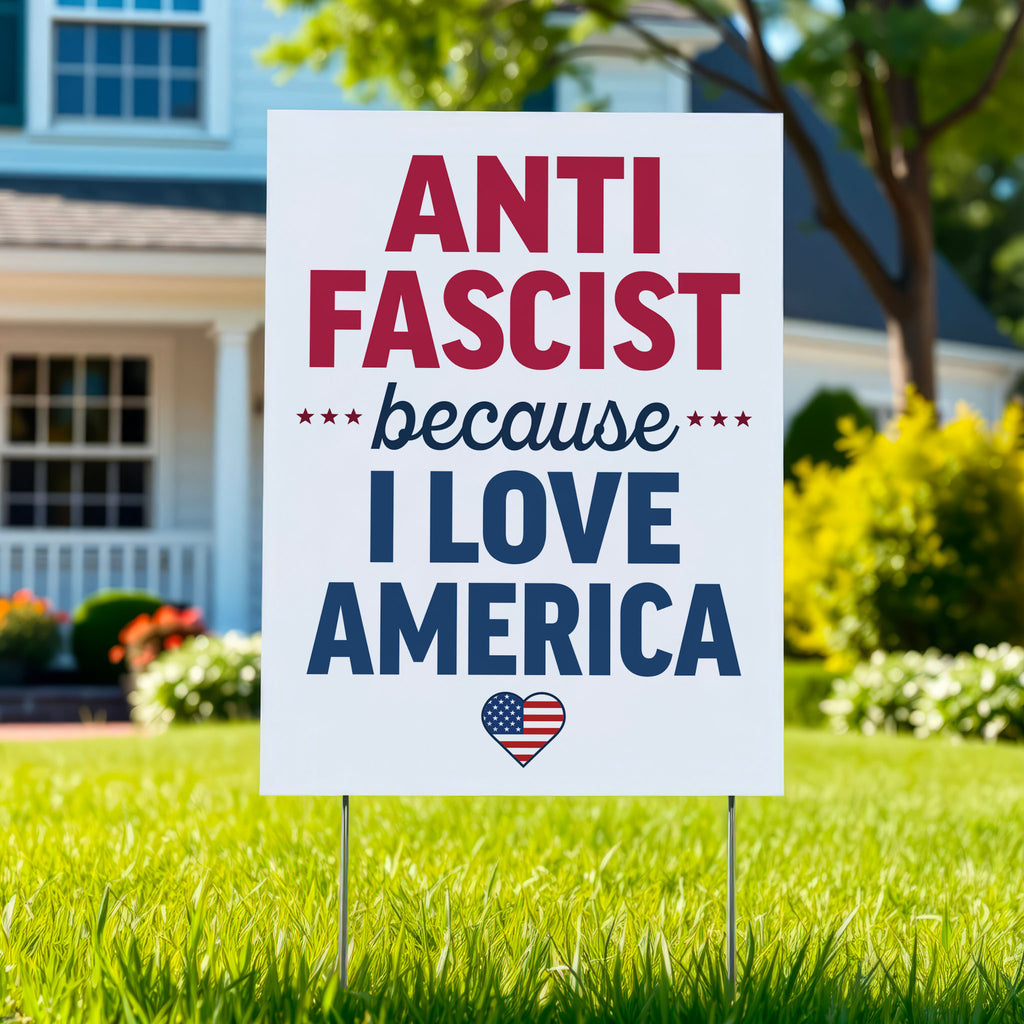 Yard sign reading “Anti-Fascist Because I Love America” in red and blue lettering with patriotic heart design, anti-Trump rally poster.