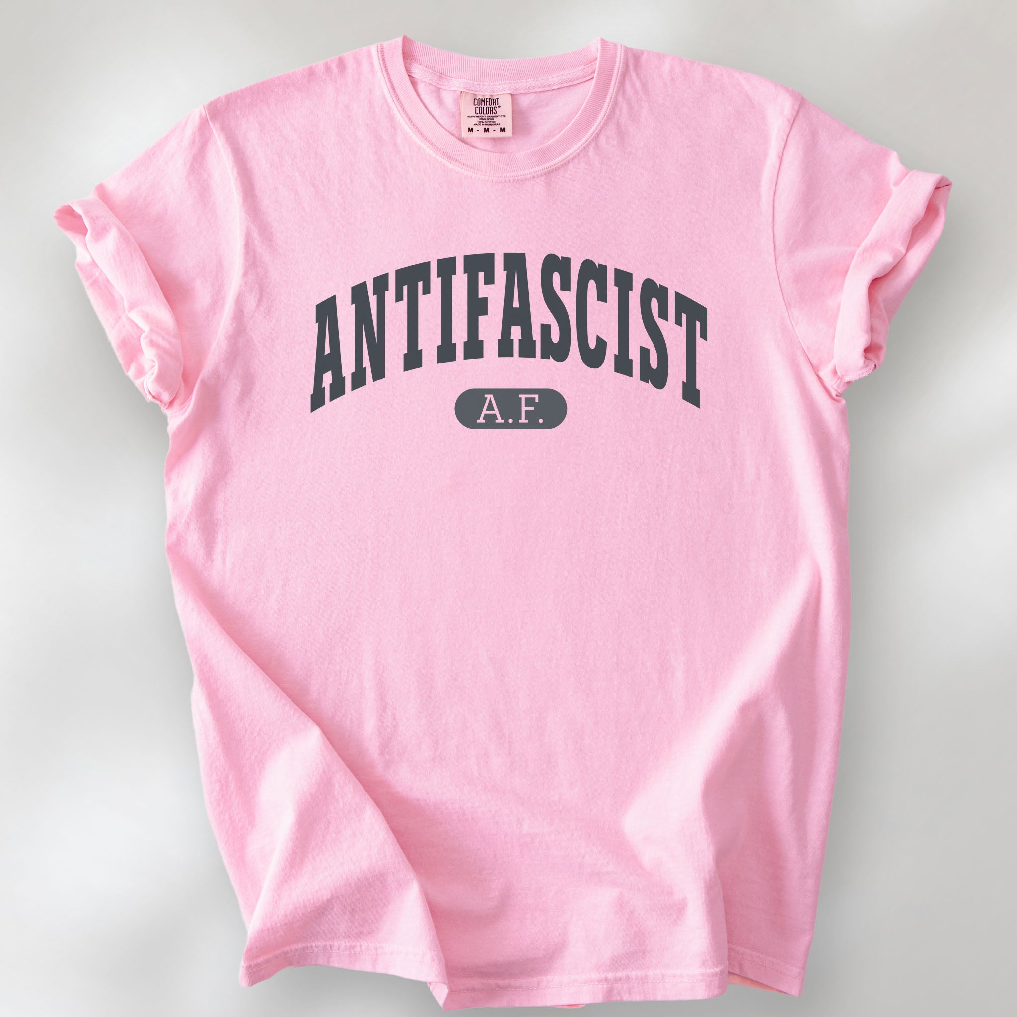Blossom Comfort Colors t-shirt with varsity collegiate style text across the front that reads "Antifascist AF."