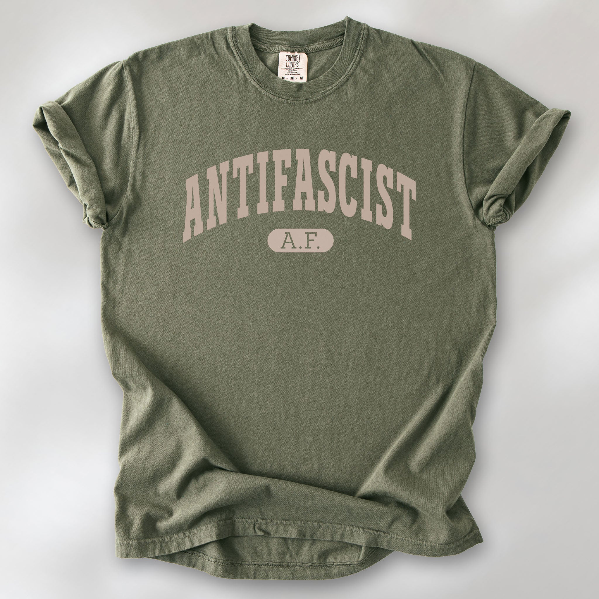 Sage Comfort Colors t-shirt with varsity collegiate style text across the front that reads "Antifascist AF."