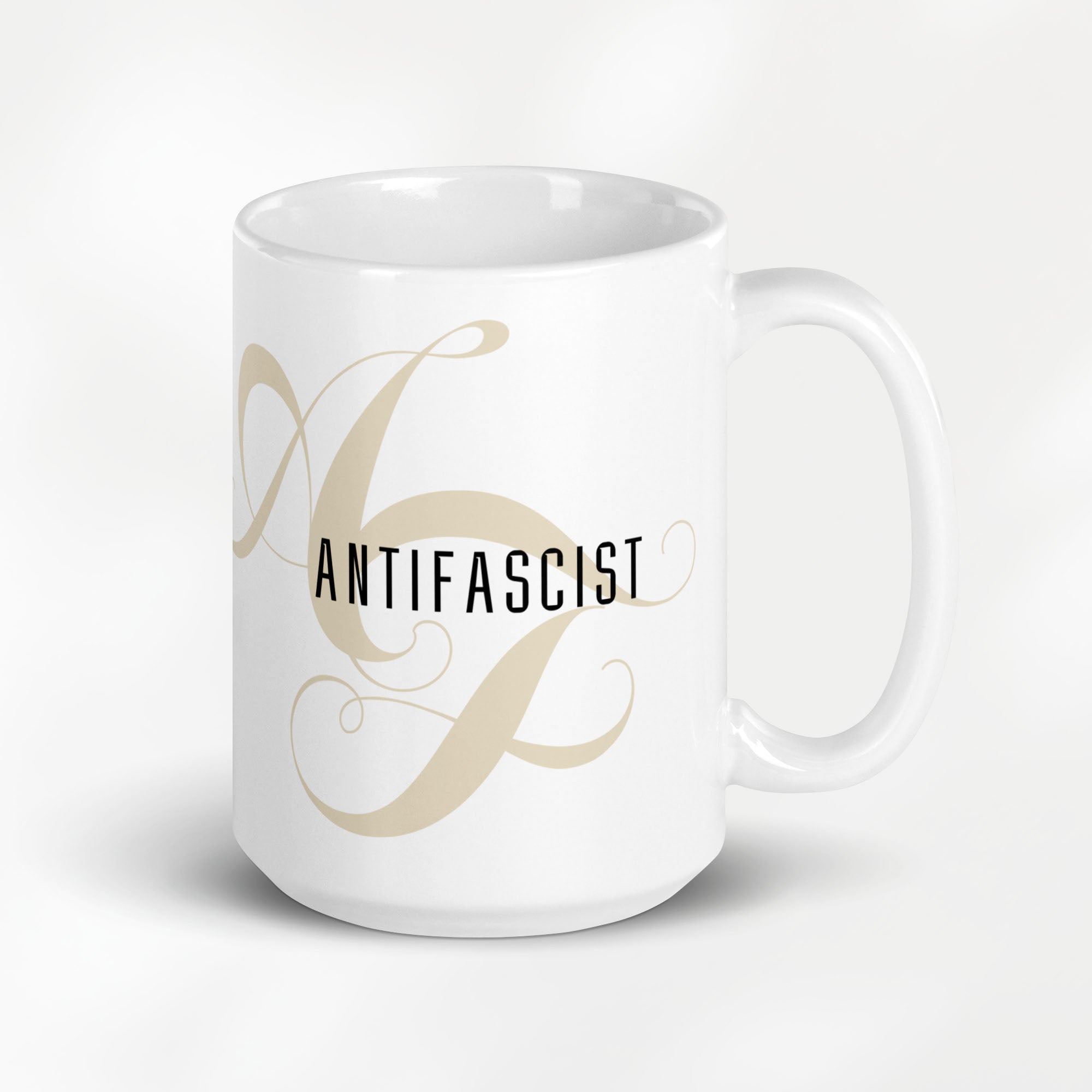 15 ounce white ceramic mug with the word “Antifascist” in black text and a subtle light tan script design of the letters A and F in the background.