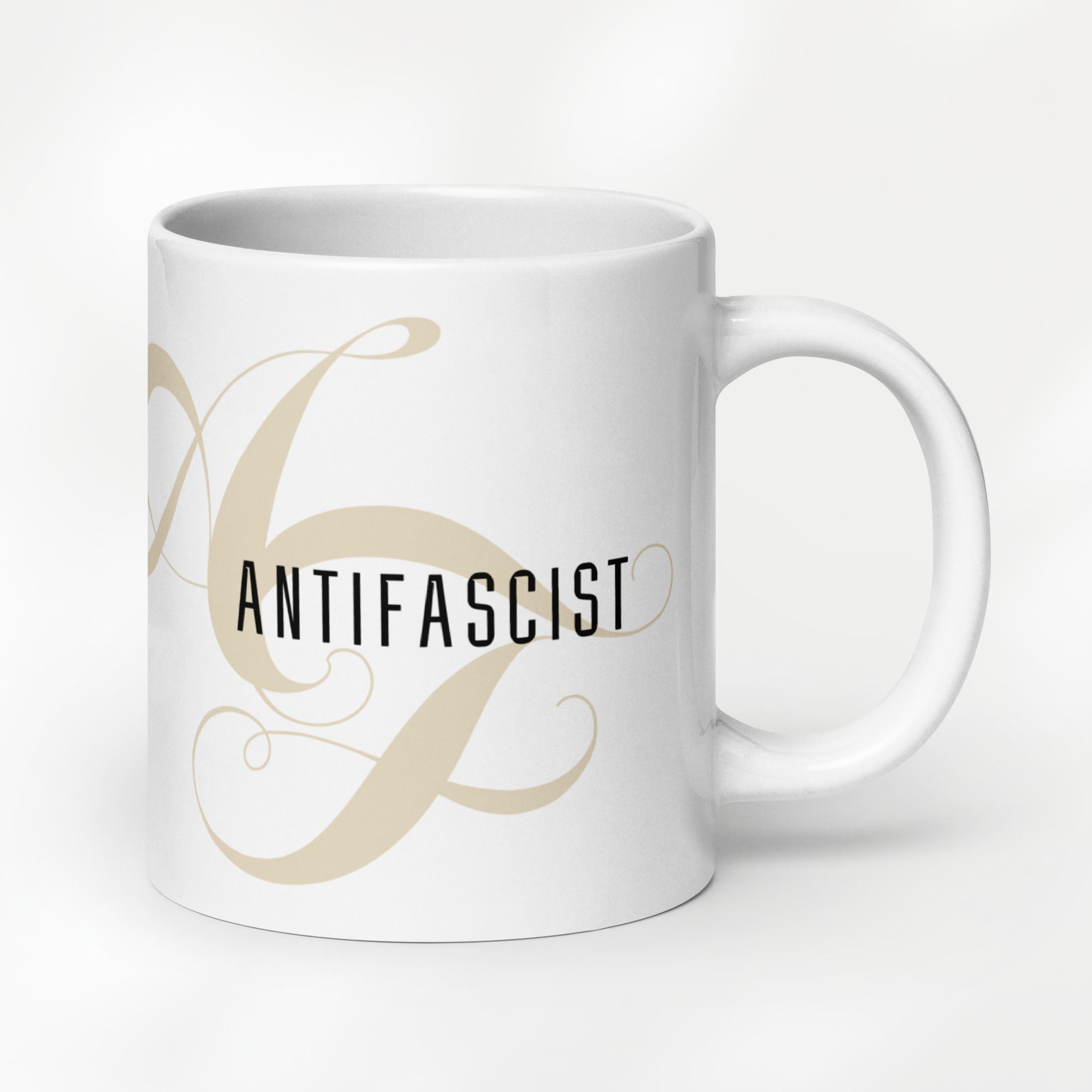 20 ounce white ceramic mug with the word “Antifascist” in black text and a subtle light tan script design of the letters A and F in the background.
