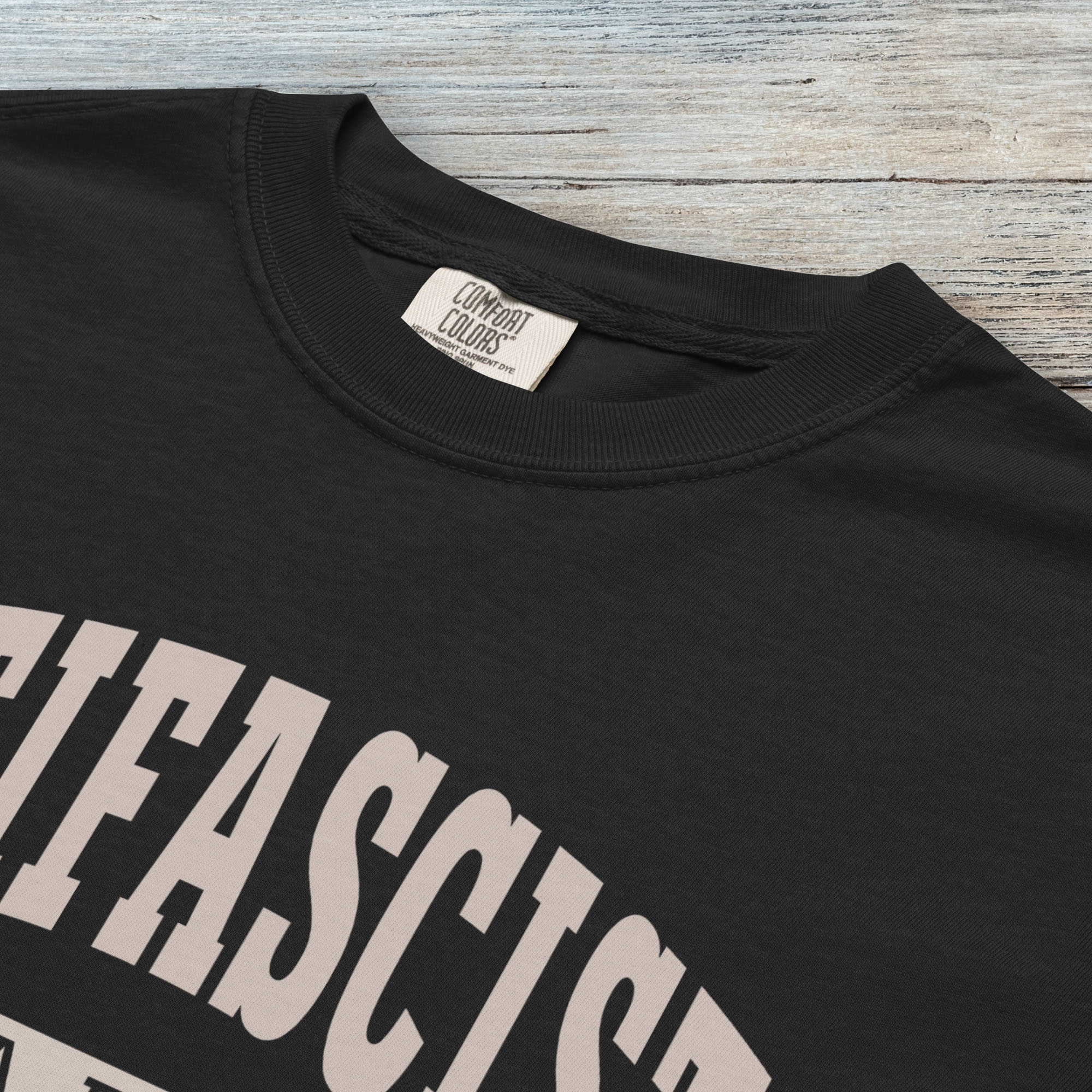 Closeup detail of back Comfort Colors t-shirt with varsity collegiate style text across the front that reads "Antifascist AF."
