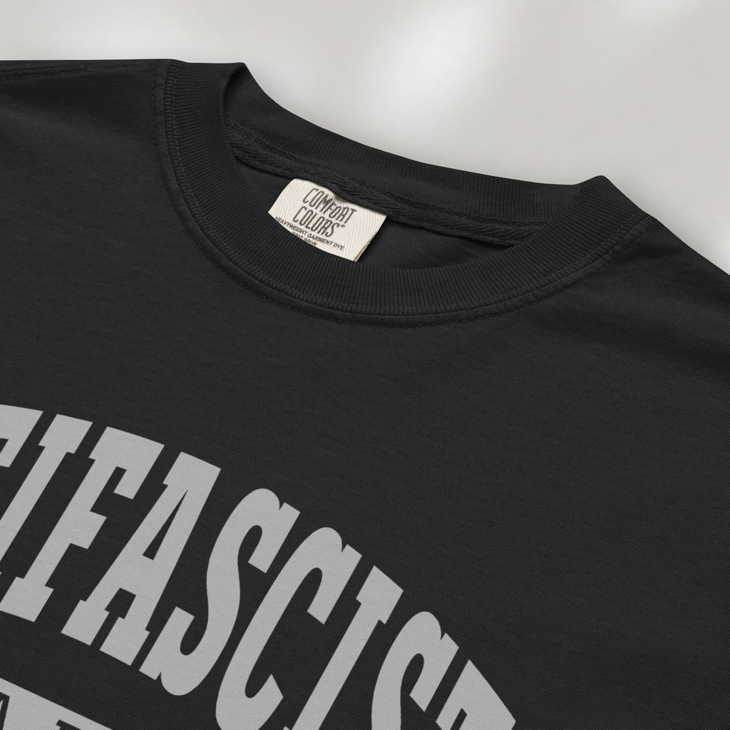 Closeup detail of black Comfort Colors t-shirt with varsity collegiate style text across the front that reads "Antifascist AF."