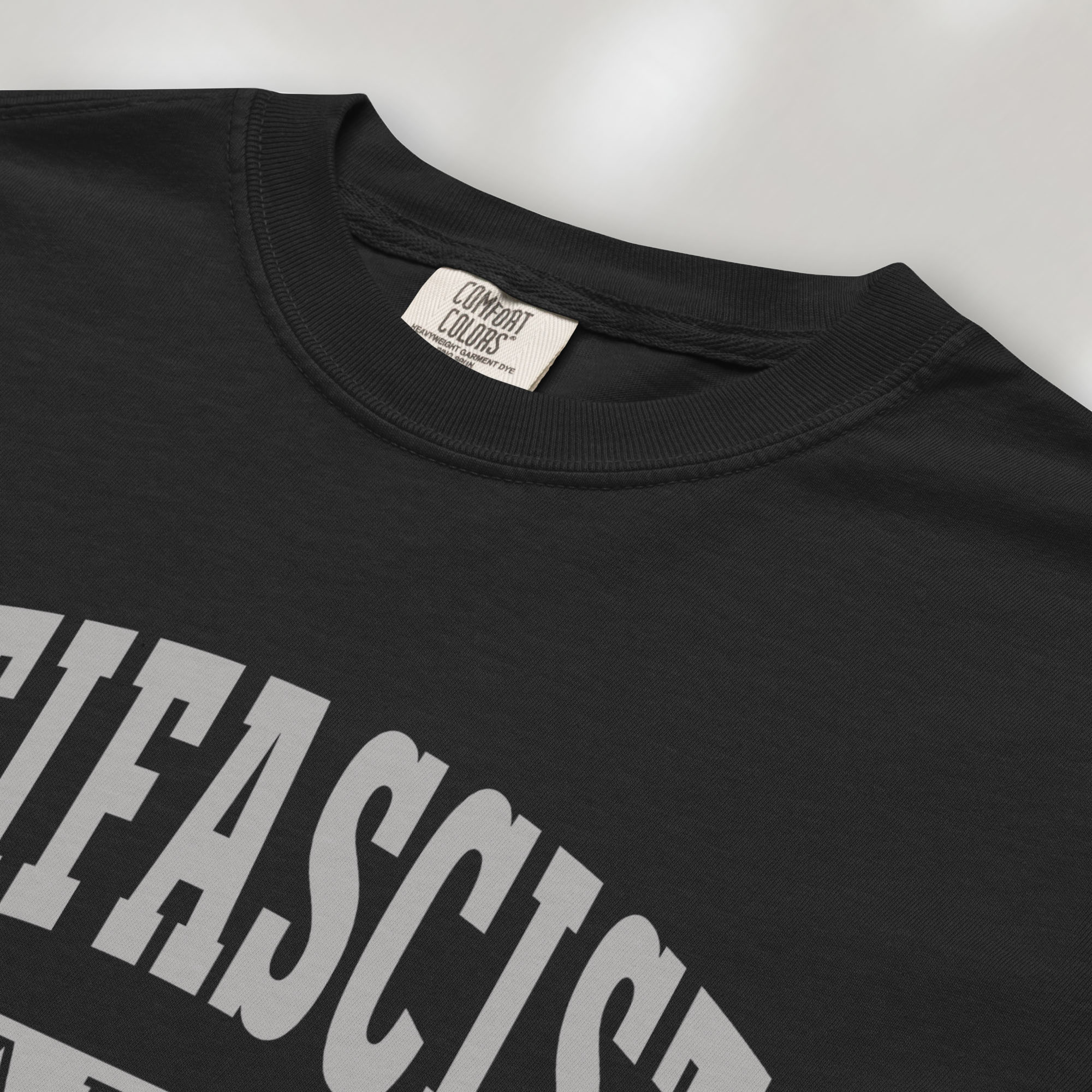Closeup detail of black Comfort Colors t-shirt with varsity collegiate style text across the front that reads "Antifascist AF."