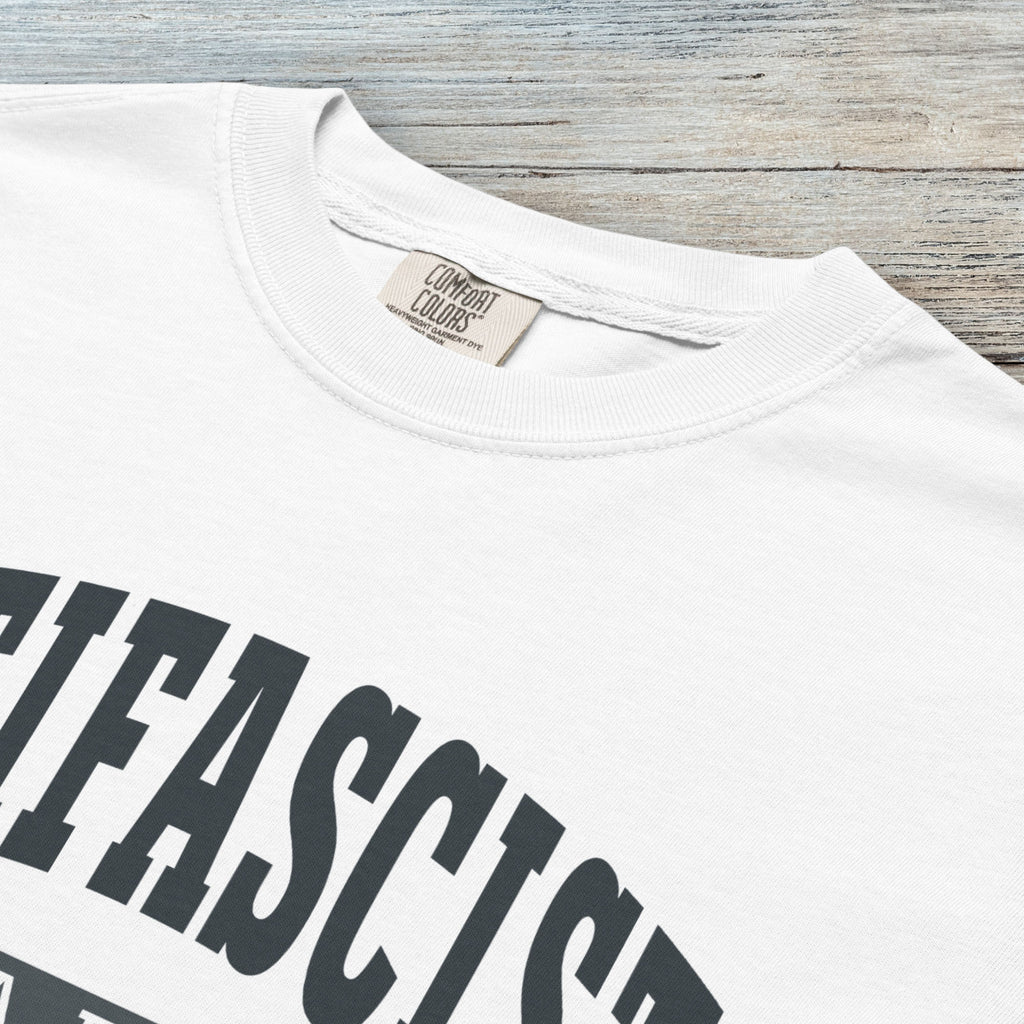 Closeup detail of white Comfort Colors t-shirt with varsity collegiate style text across the front that reads "Antifascist AF."
