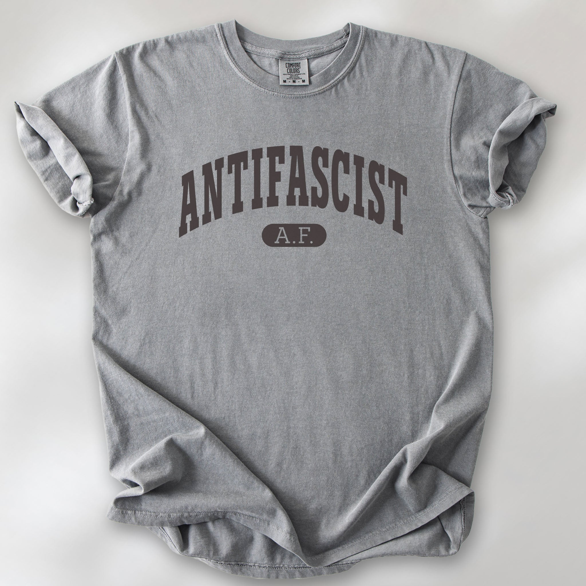 Grey Comfort Colors t-shirt with varsity collegiate style text across the front that reads "Antifascist AF."