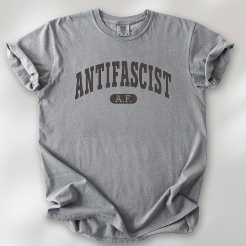 Grey Comfort Colors t-shirt with varsity collegiate style text across the front that reads "Antifascist AF."
