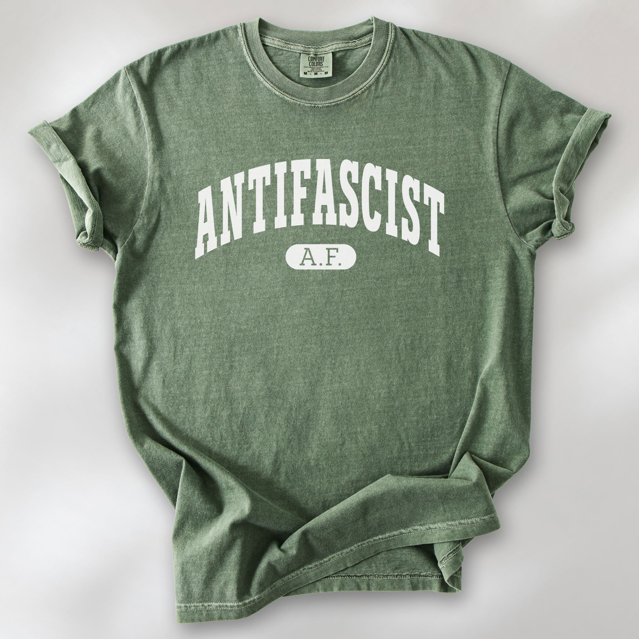 Moss Comfort Colors t-shirt with varsity collegiate style text across the front that reads "Antifascist AF."
