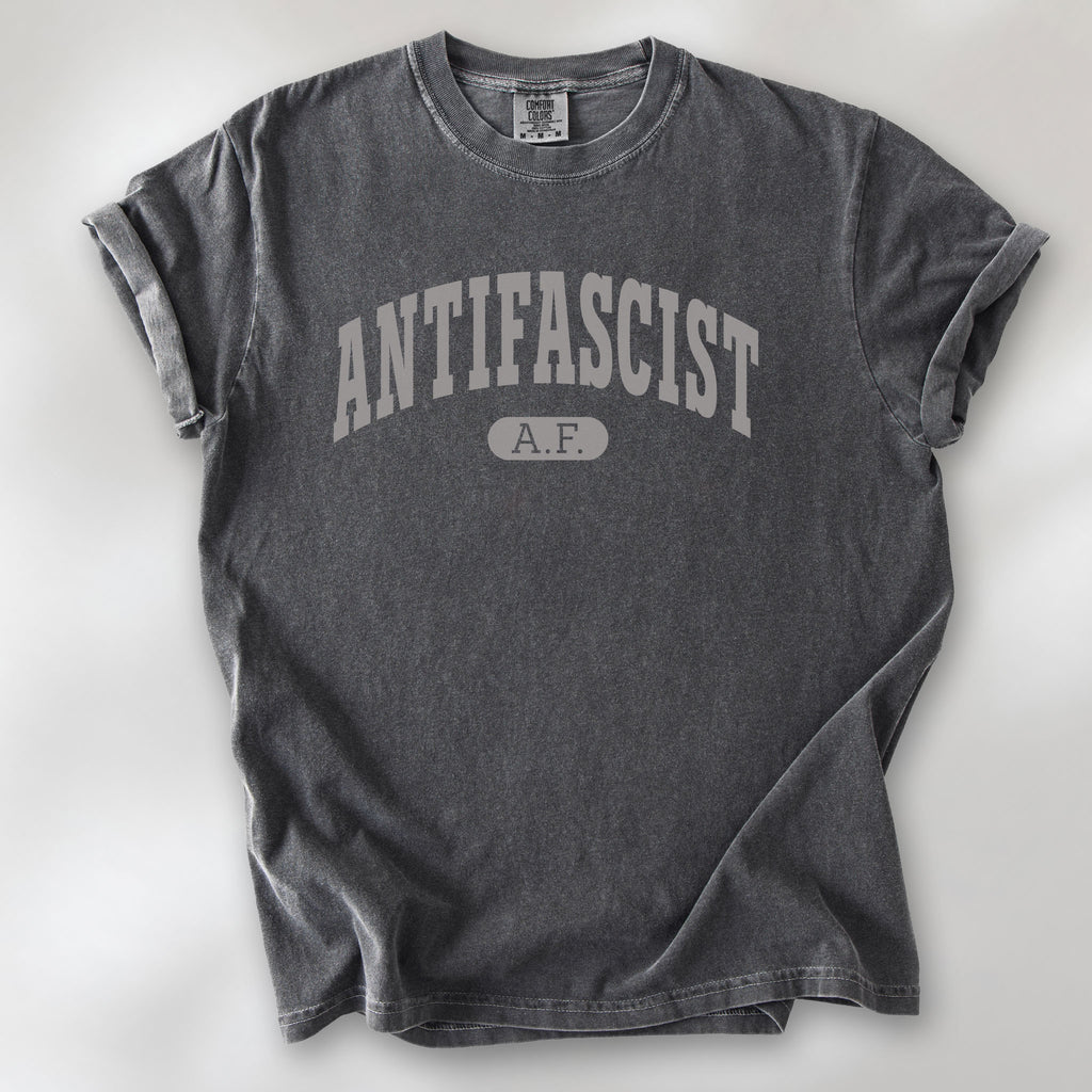 Pepper Comfort Colors t-shirt with varsity collegiate style text across the front that reads "Antifascist AF."