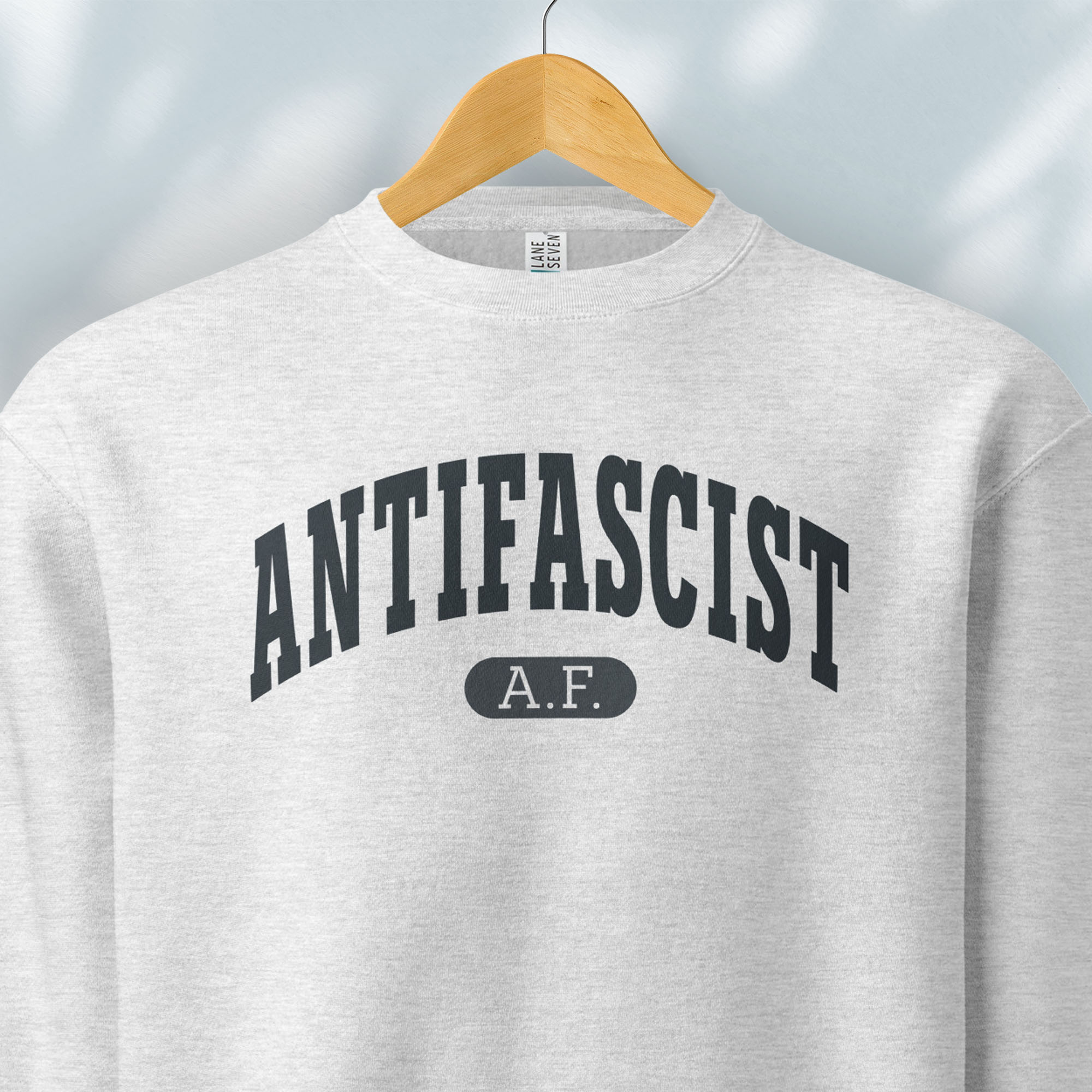 Hanging grey crewneck sweatshirt with varsity collegiate style text across the front that reads "Antifascist AF."